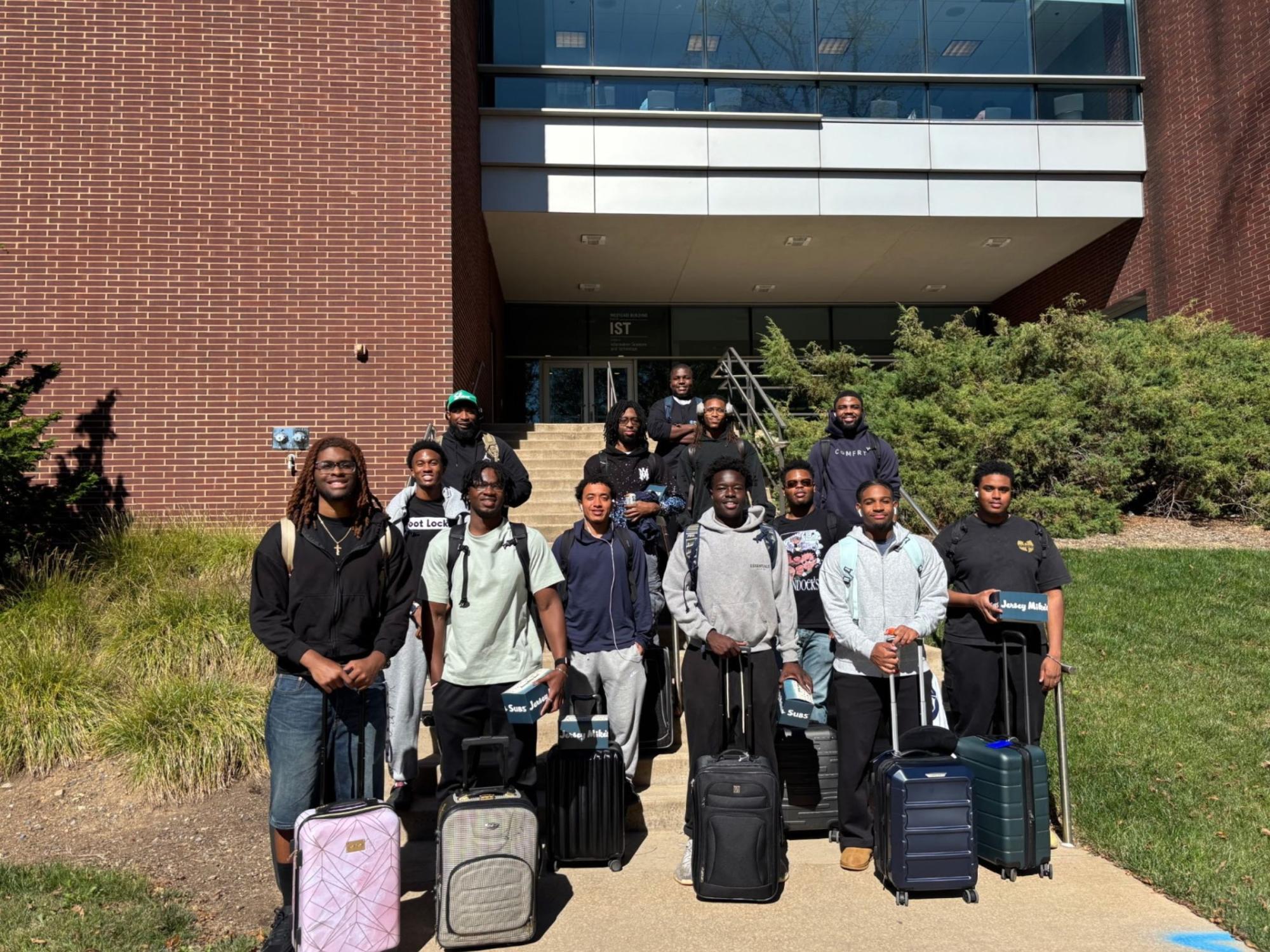 group of people with suitcases in front of brick building