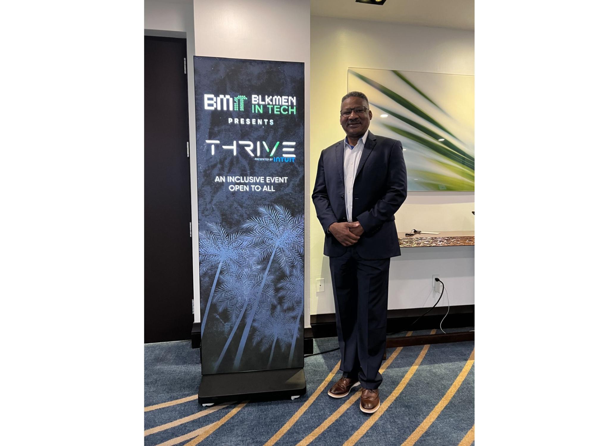 person in suit standing next to conference sign
