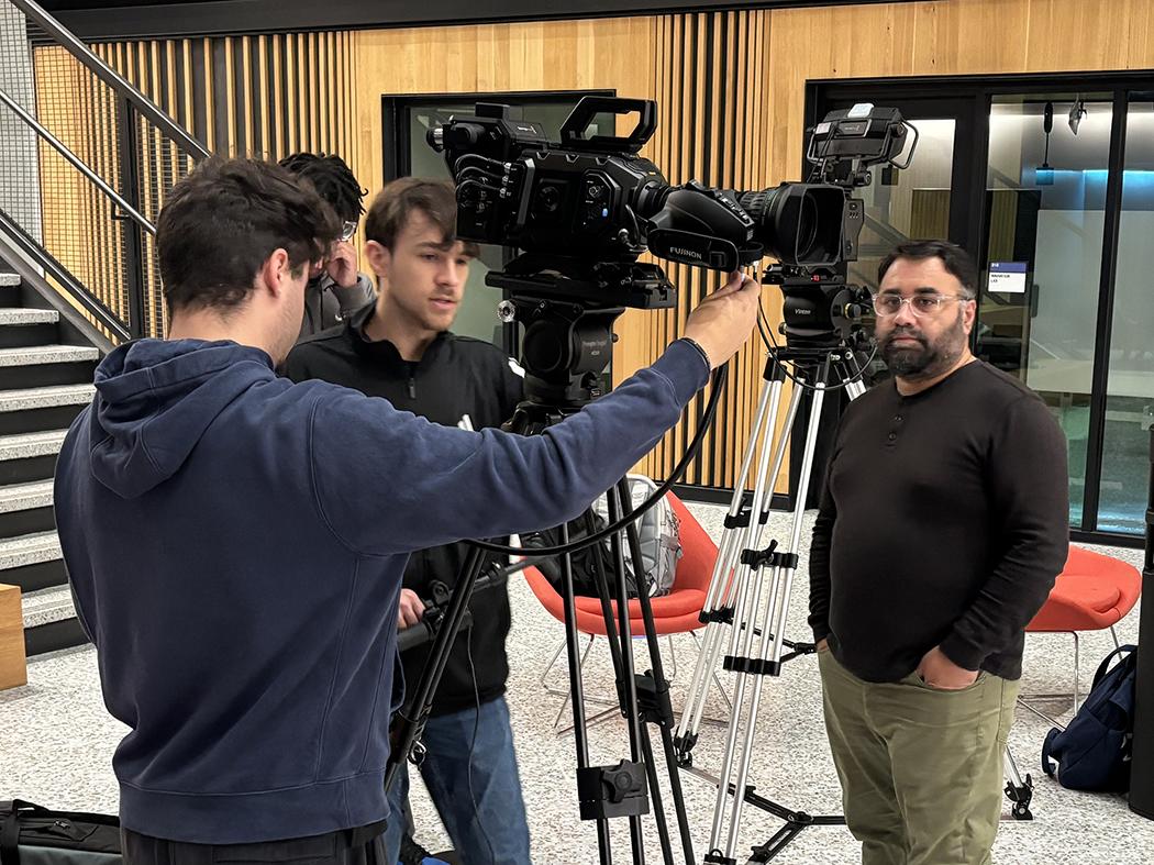 Four men huddled around a camera