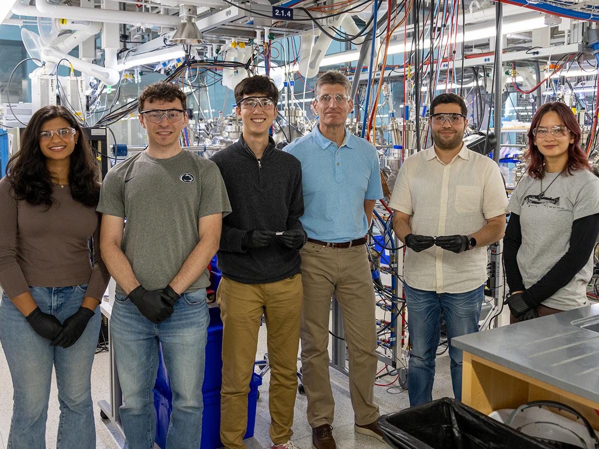 Six people wearing safety glasses pose for a photo in a lab