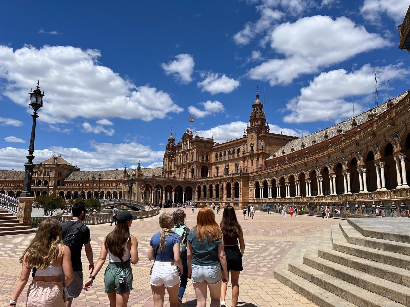 A group of students walk in front of the Plaza de España in Sevilla, Spain.