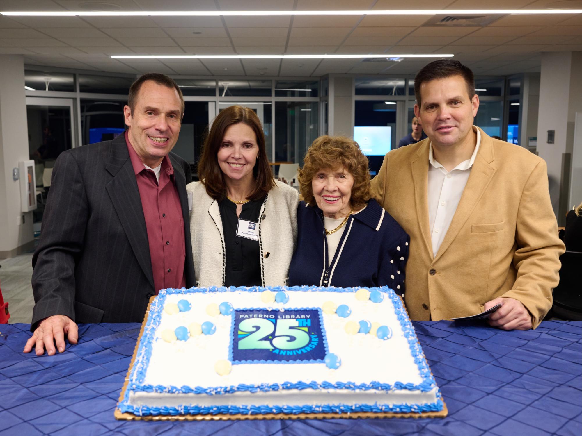 older woman with two adult men and one adult woman standing in front of cake