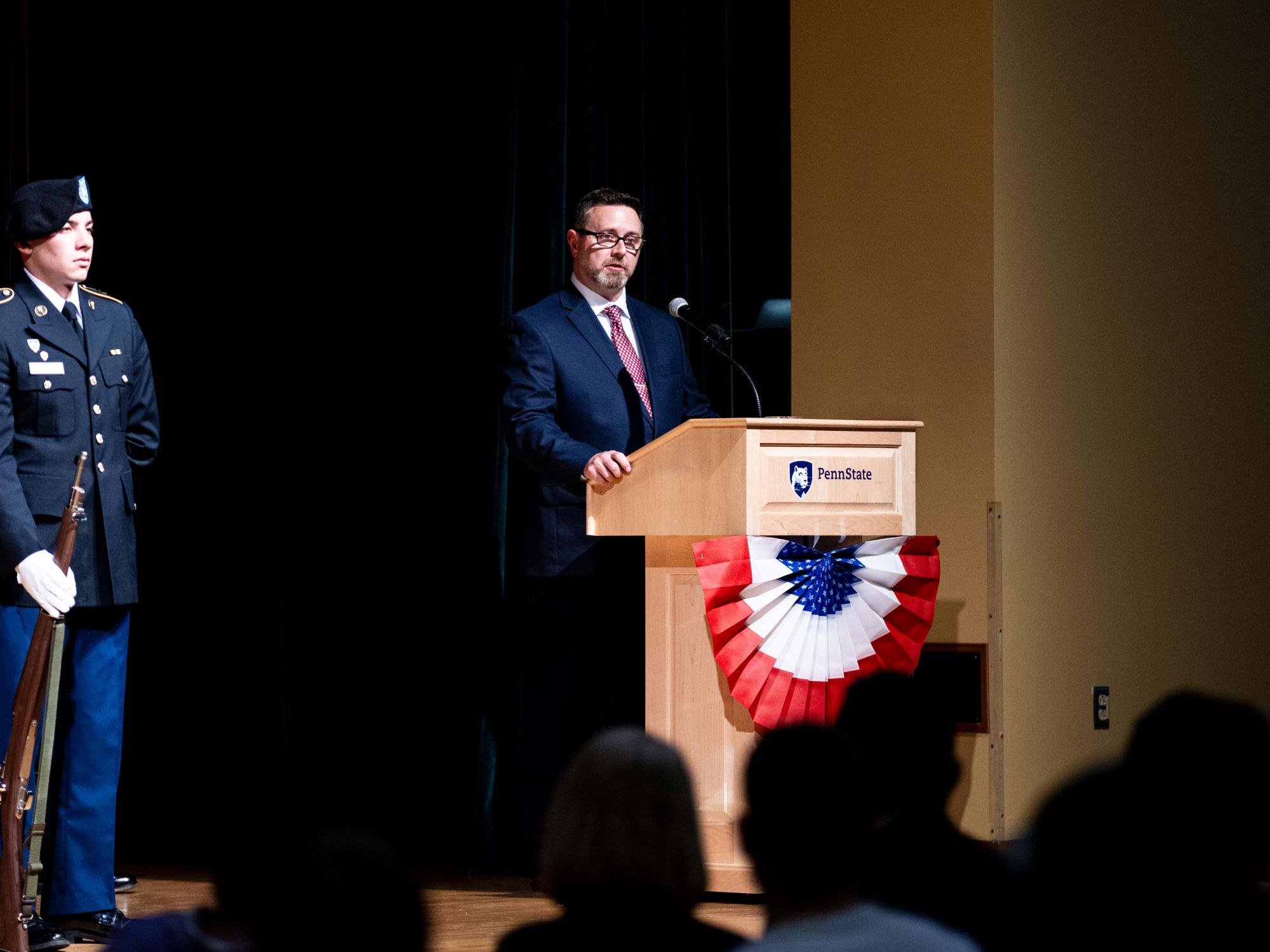 A person standing at podium speaking to the crowd