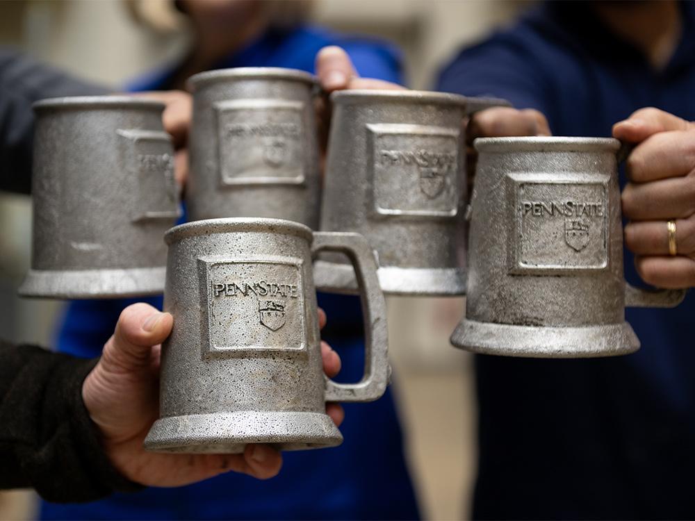 Researchers tapping mugs together, which are Penn State branded and created with lost foam casting, one of the several casting approaches possible in the new Penn State facility. 