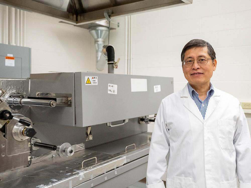Person standing in lab, looking at camera and smiling.