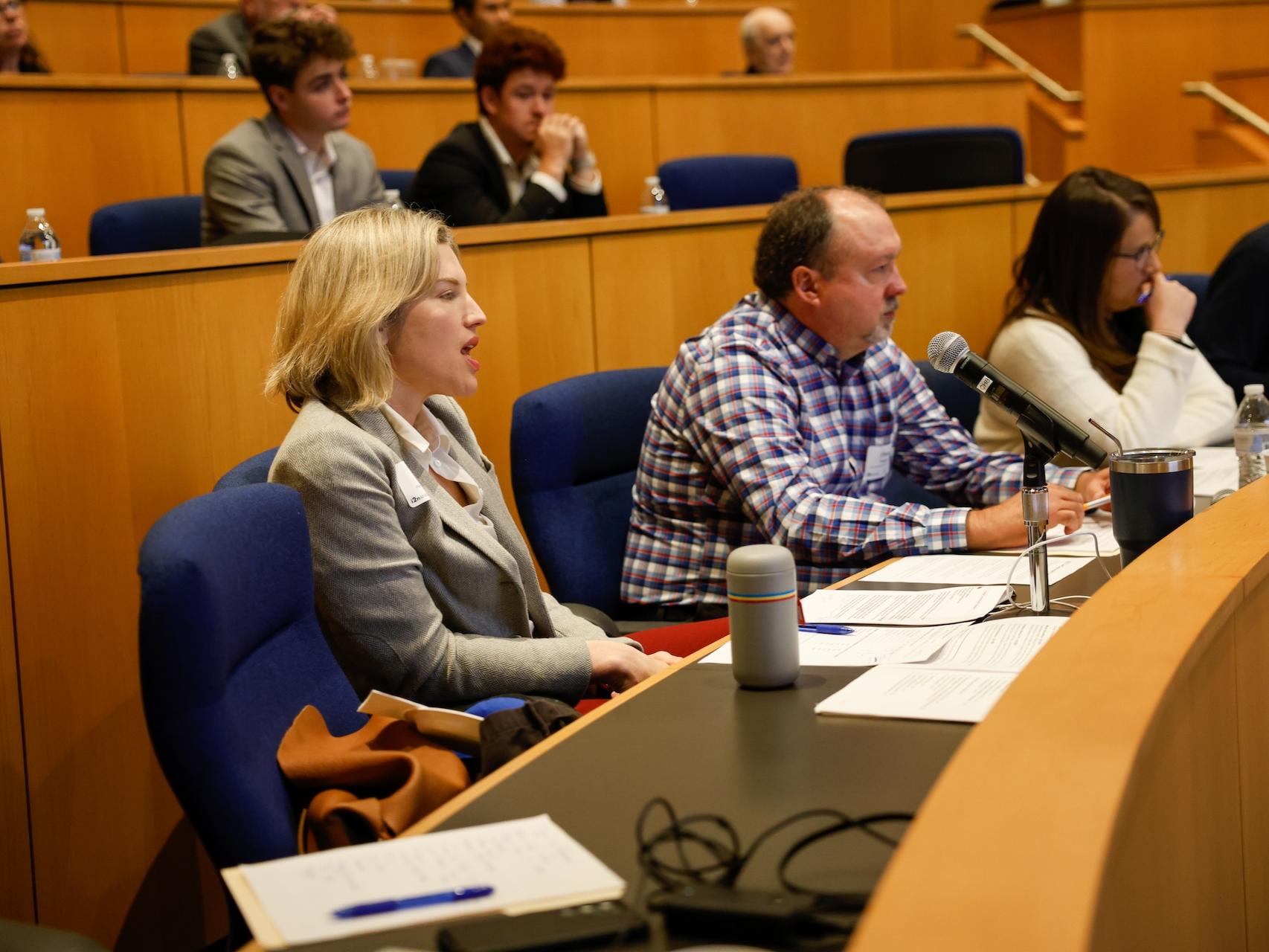 Annie Hughes speaking as a judge, with other judges next to her. 