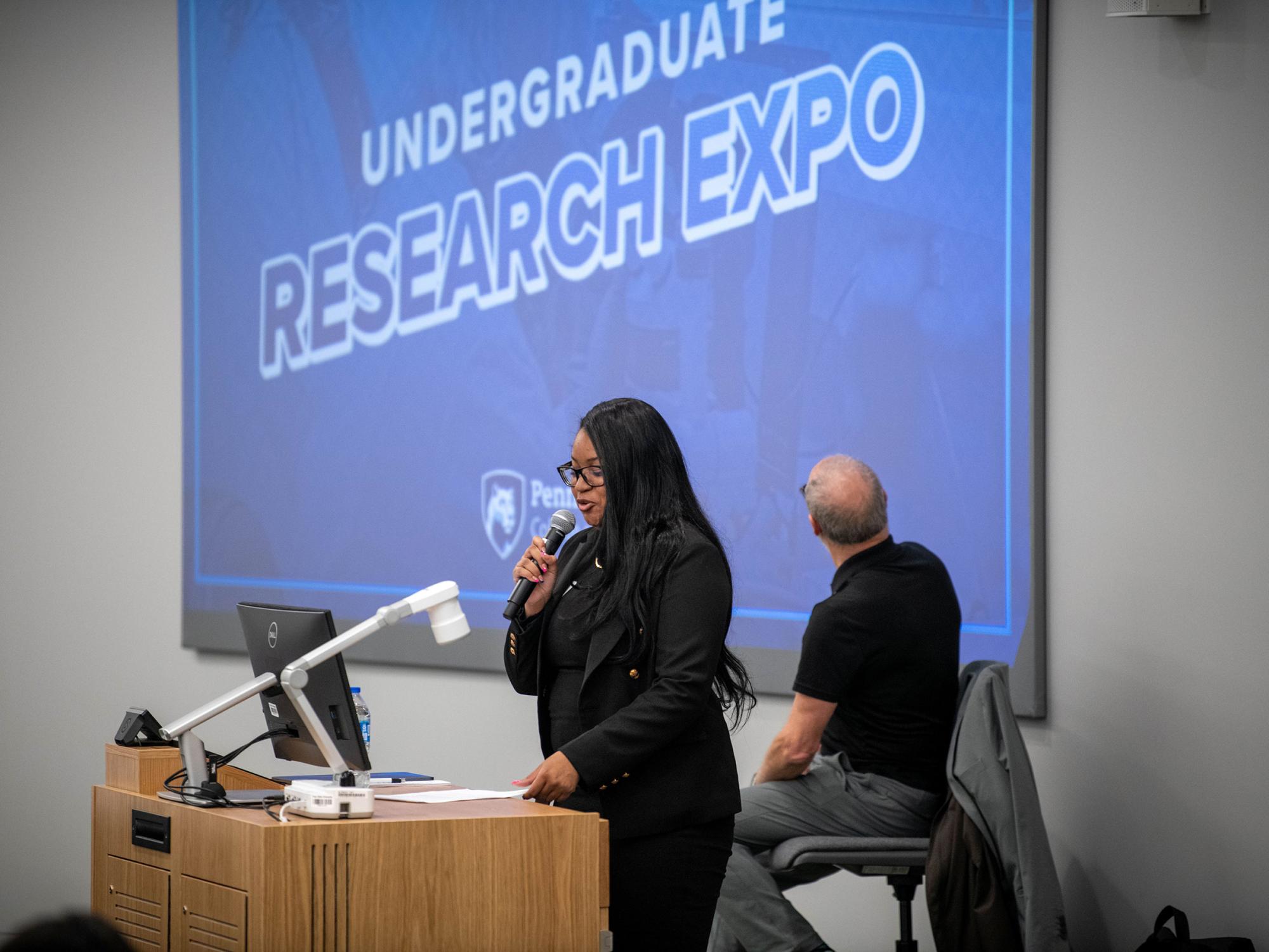a student researcher presents at a podium
