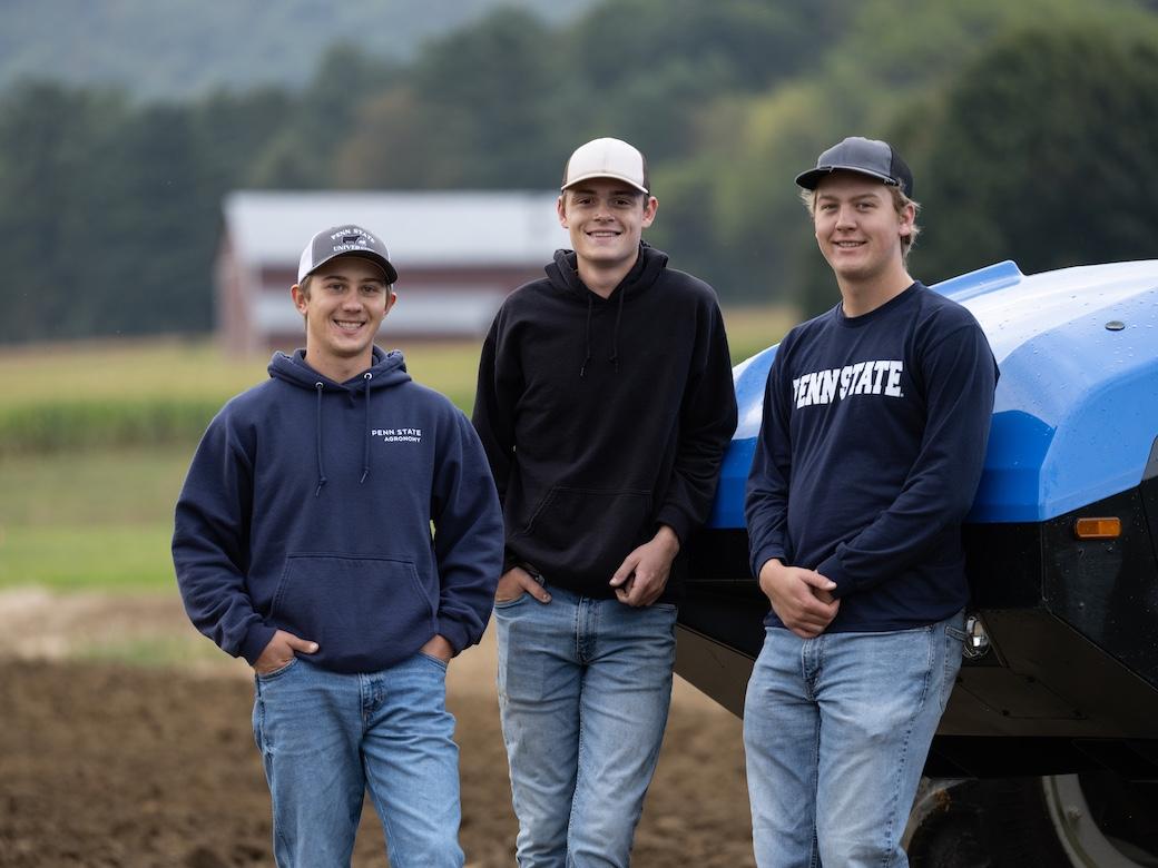 Three students stand together in an agriculture field at Penn State.