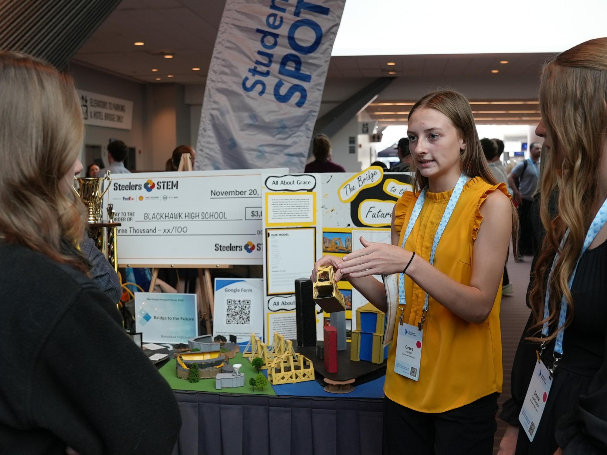 Students presenting a STEM project display at an event.