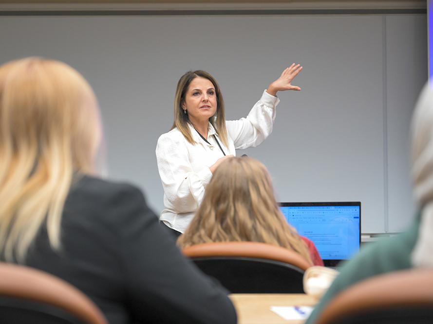 A woman in a white shirt speaks to an audience