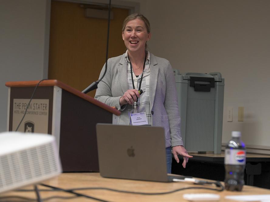 A woman in a gray jacket makes a presentation to an audience