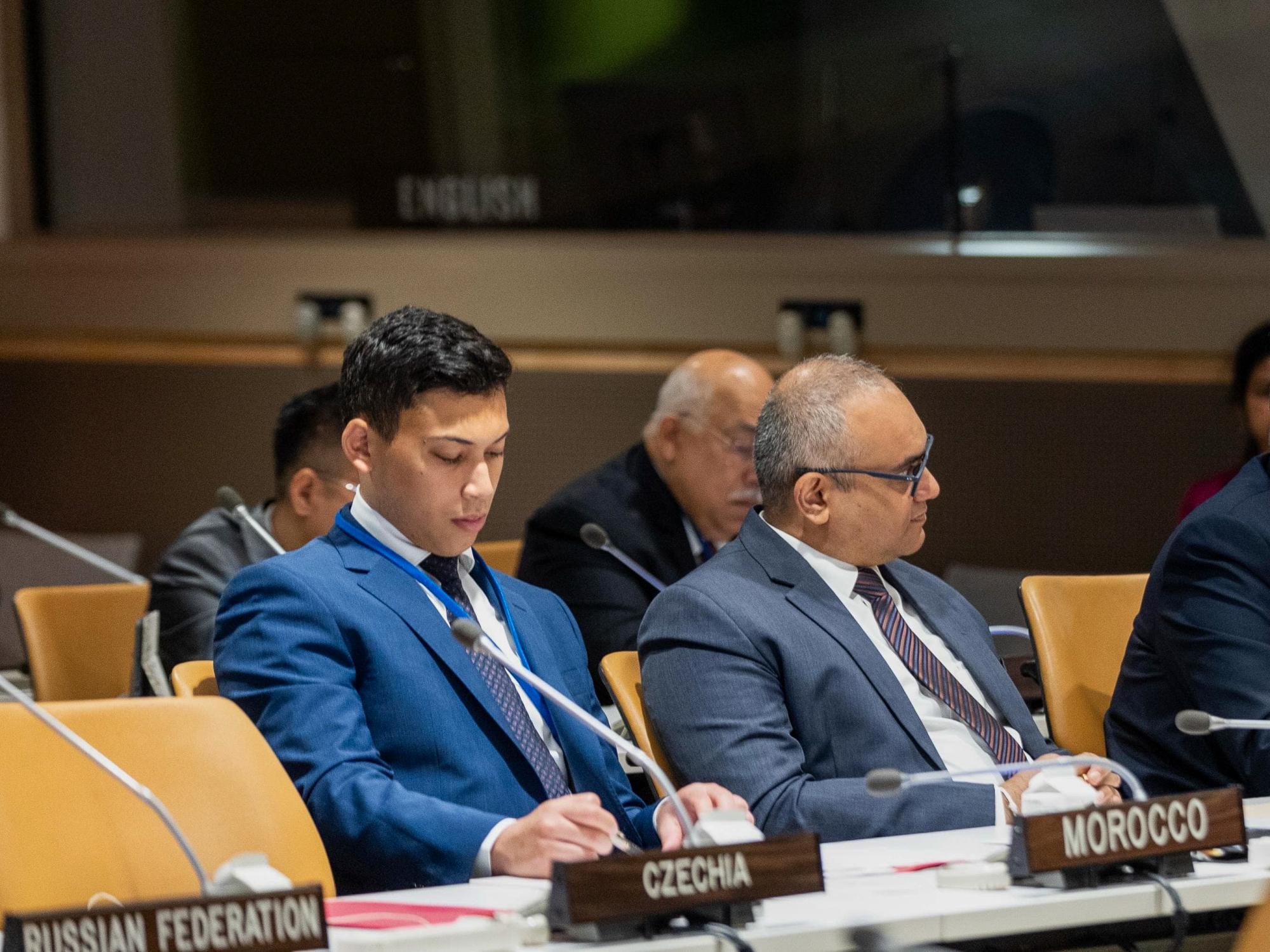 Ahmed Al Saleh wears a blue suit and takes notes while attending a session of the United Nations.
