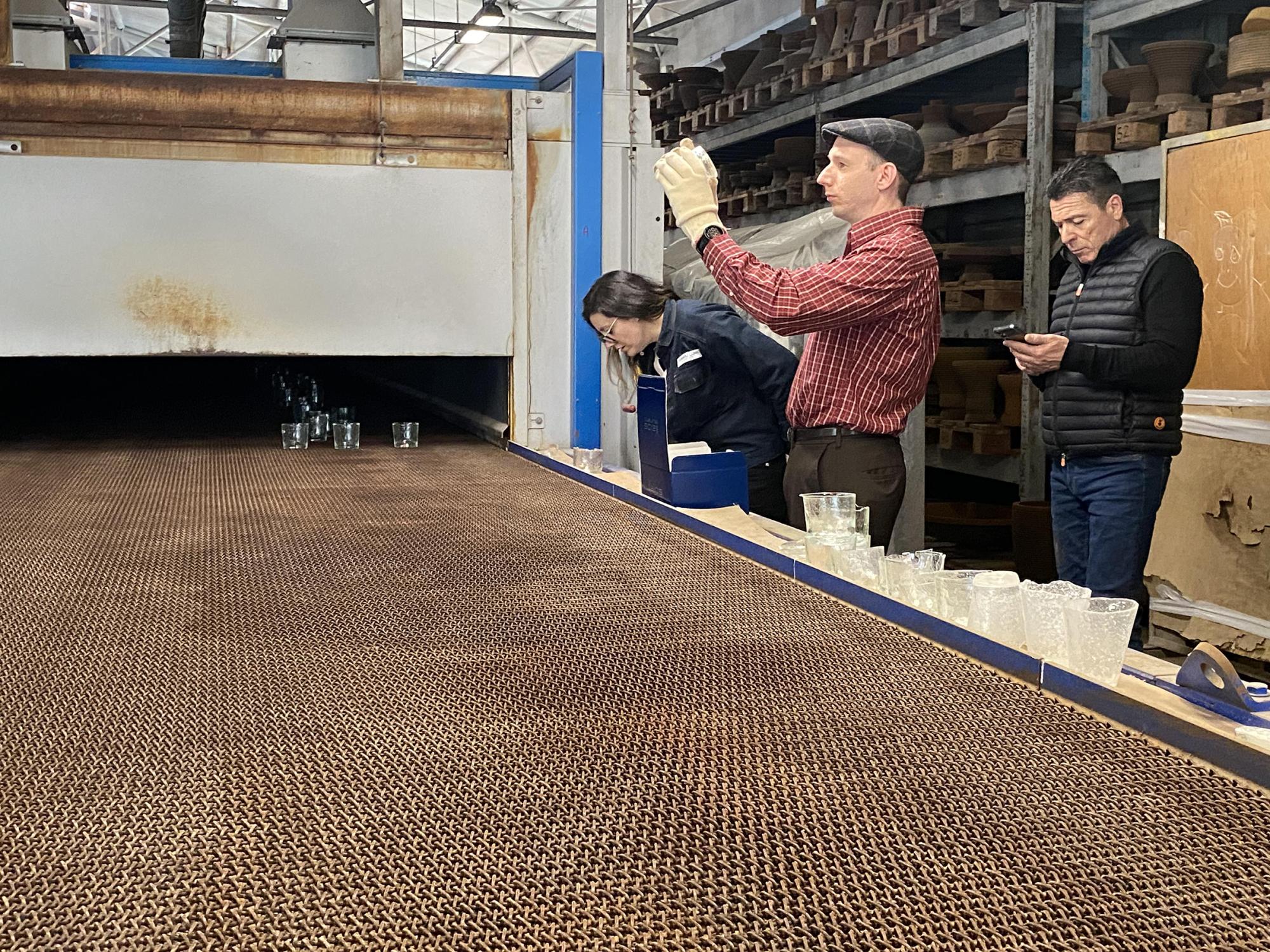A conveyor belt with glass objects on it