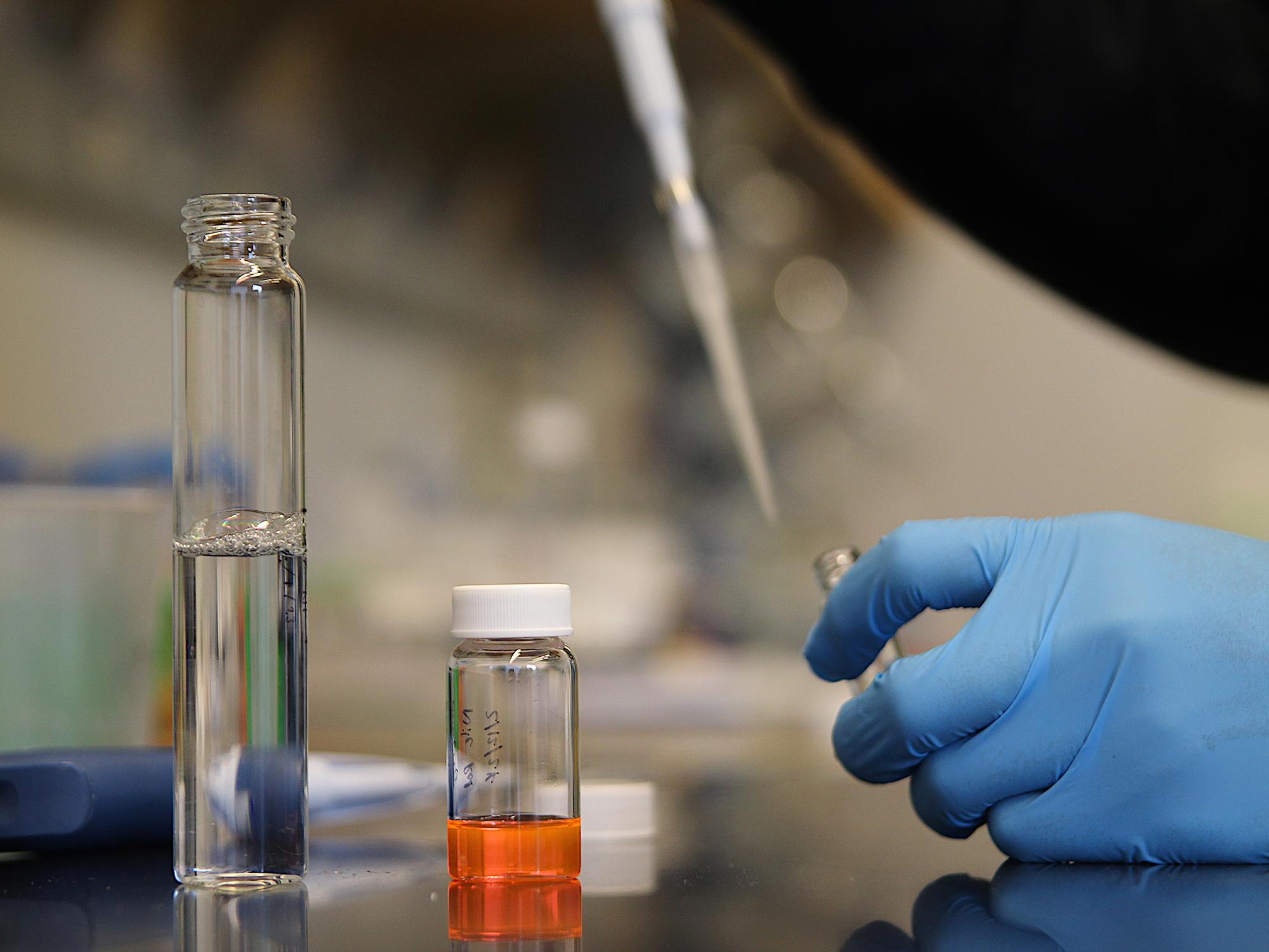 gloved hands pipetting a solution