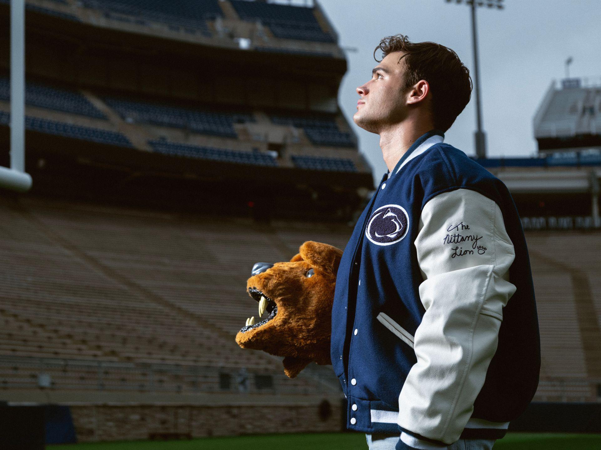 A side portrait of a student holding the Nittany Lion mascot head