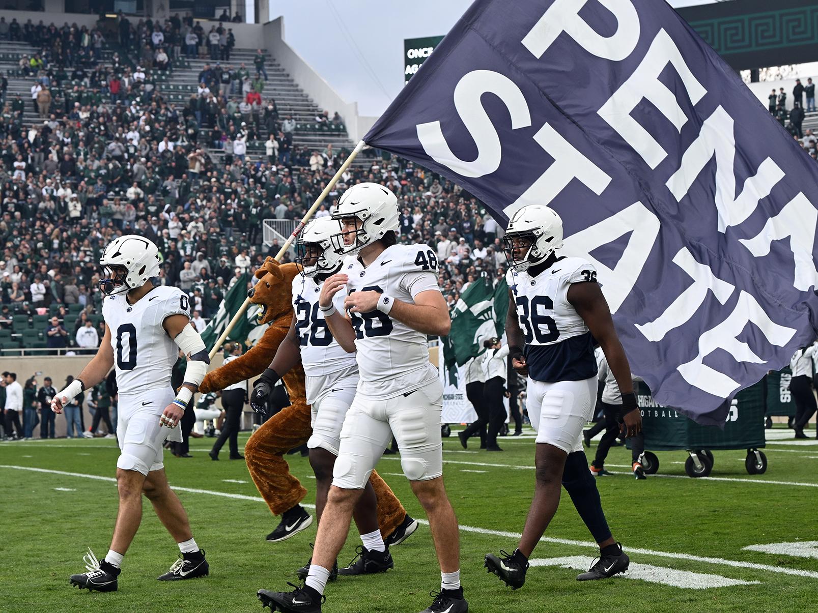 Team walks on field with lion and banner