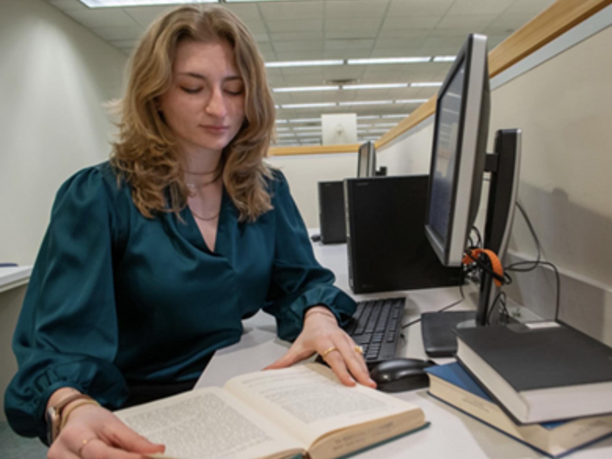 A student at a computer and reading book