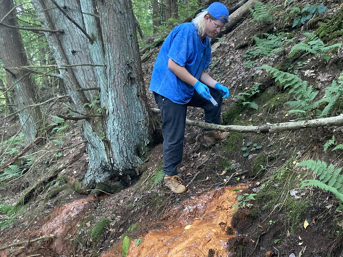 A person climbs up a creek bank. 