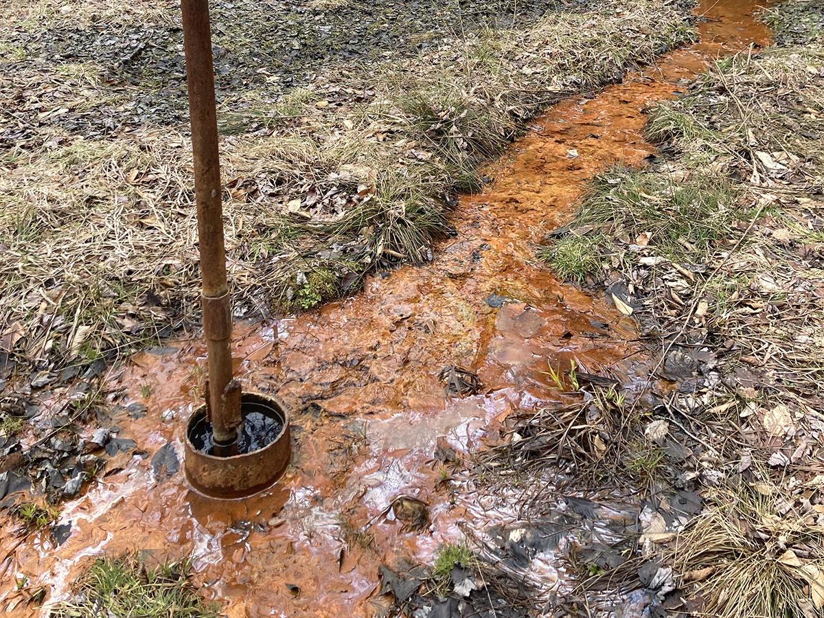 Red-stained water leaks out from a rusted pipe. 