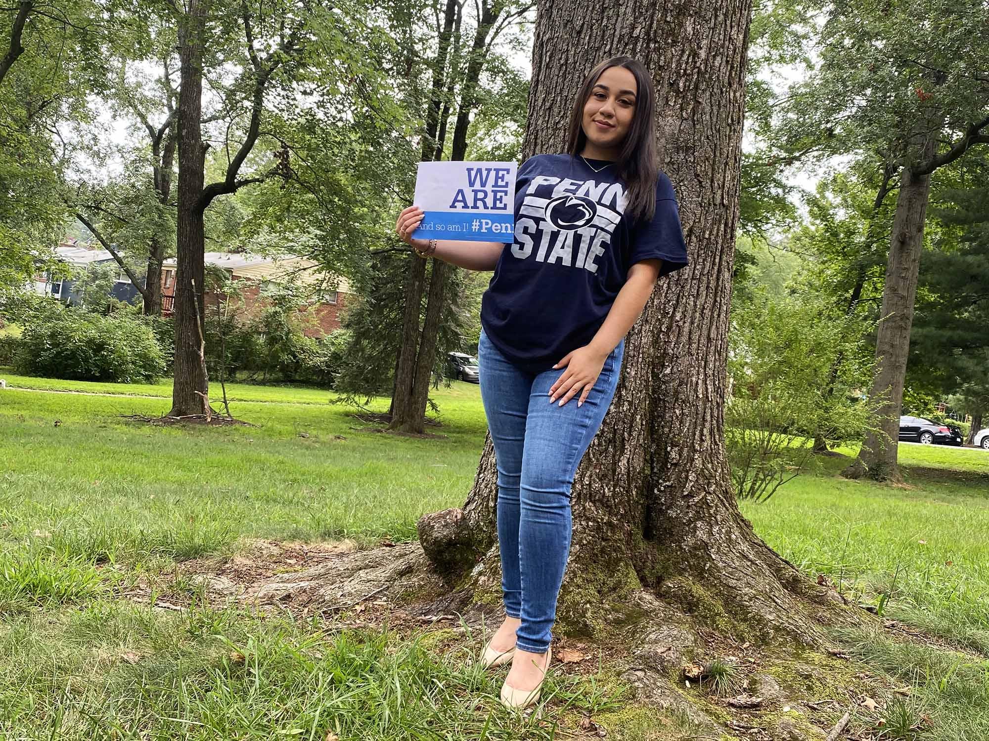 A woman wearing a Penn State t-shirt holds a sign that says "We Are"