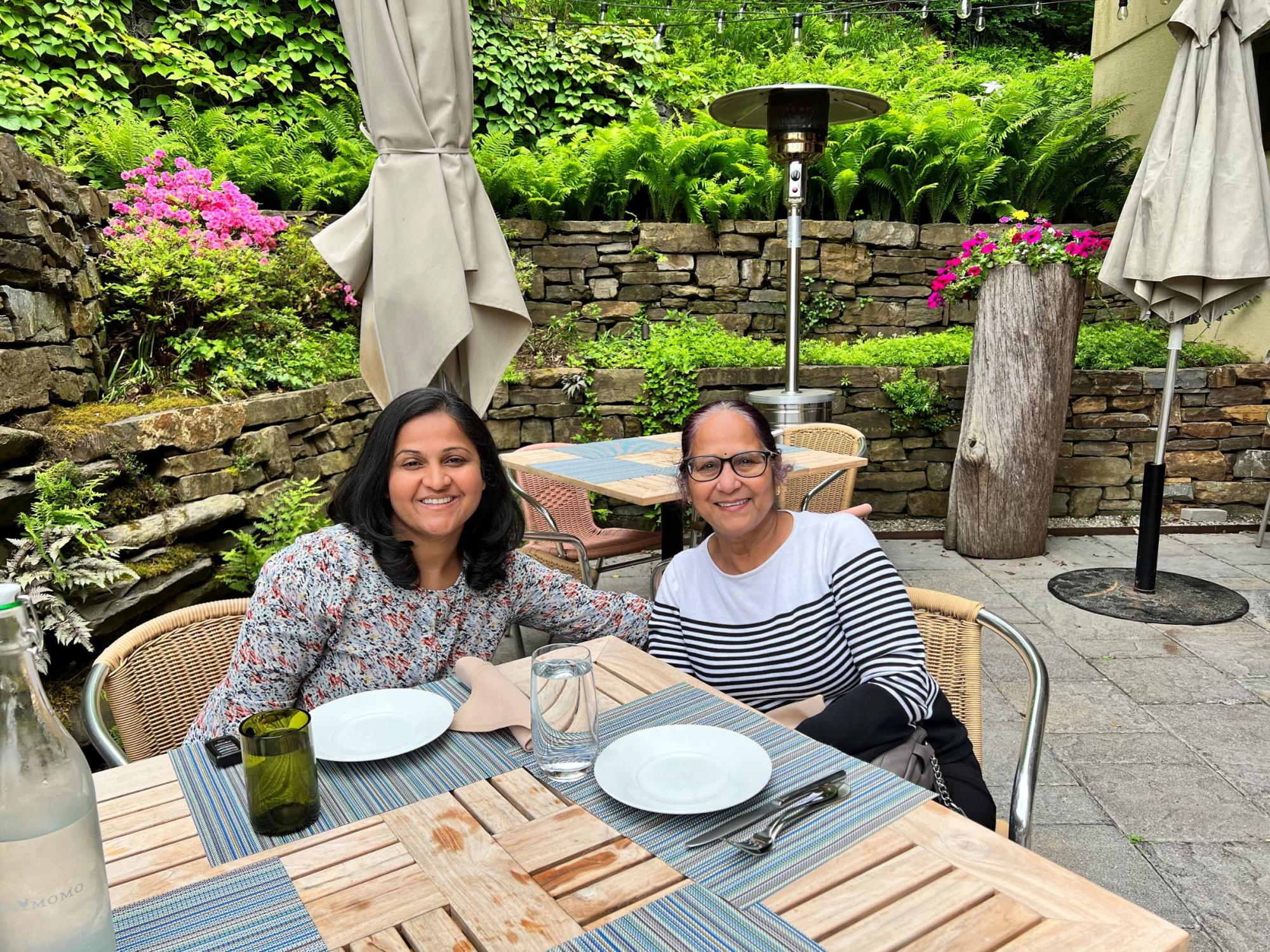 daughter and mother seated at outdoor patio table