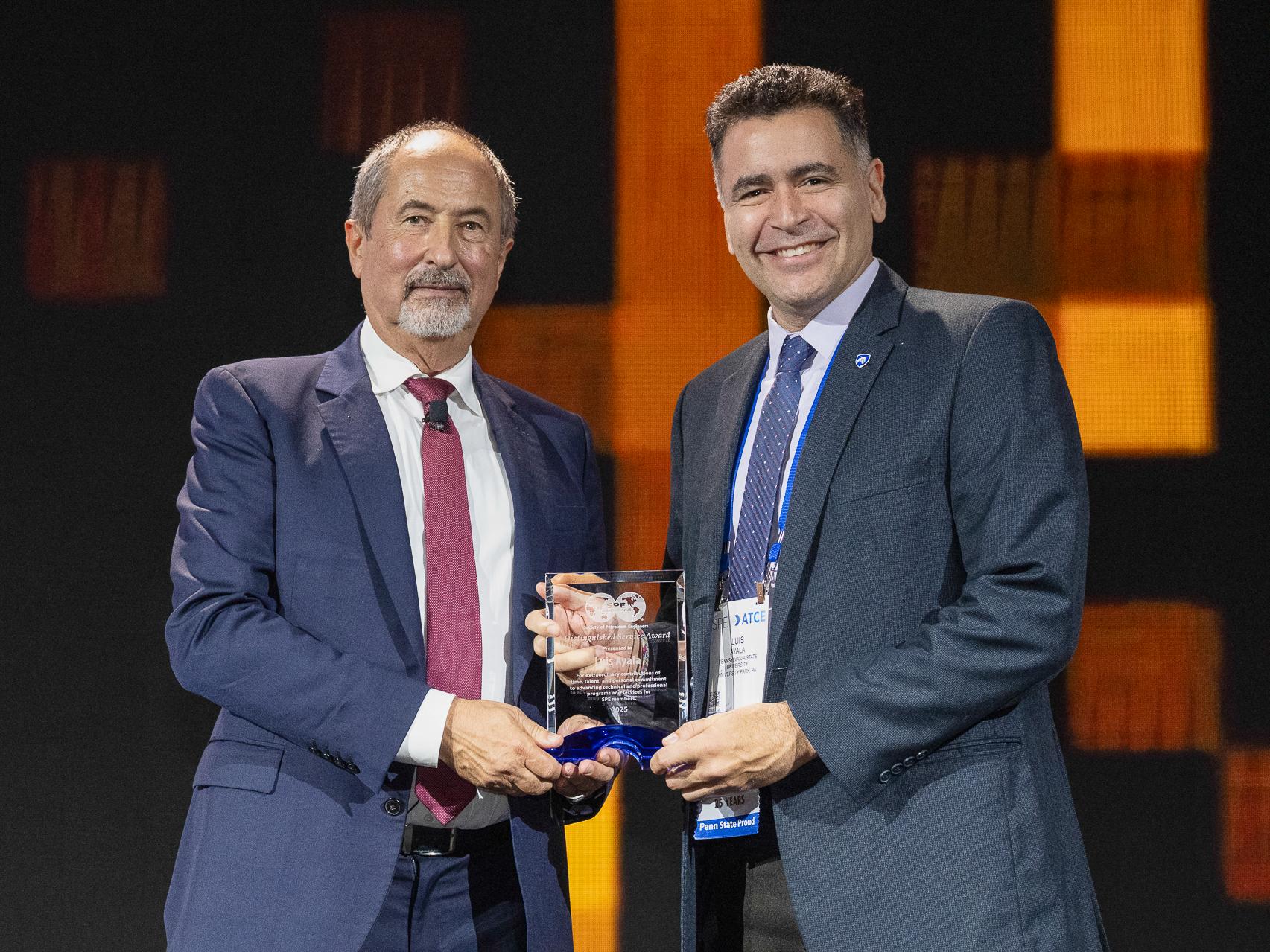 Luis F. Ayala H. on stage receiving award from SPE president.