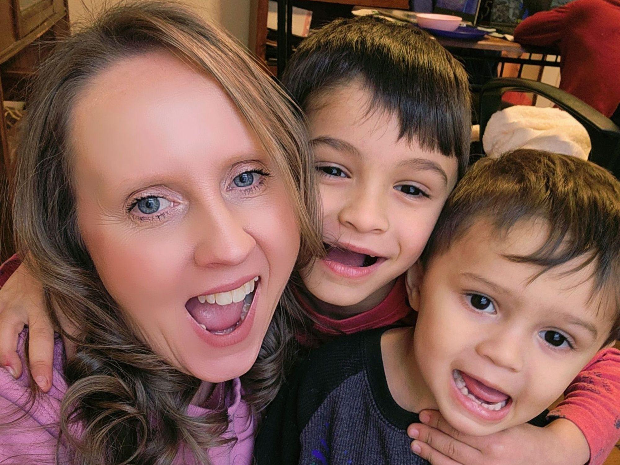a woman poses while hugging her two small children