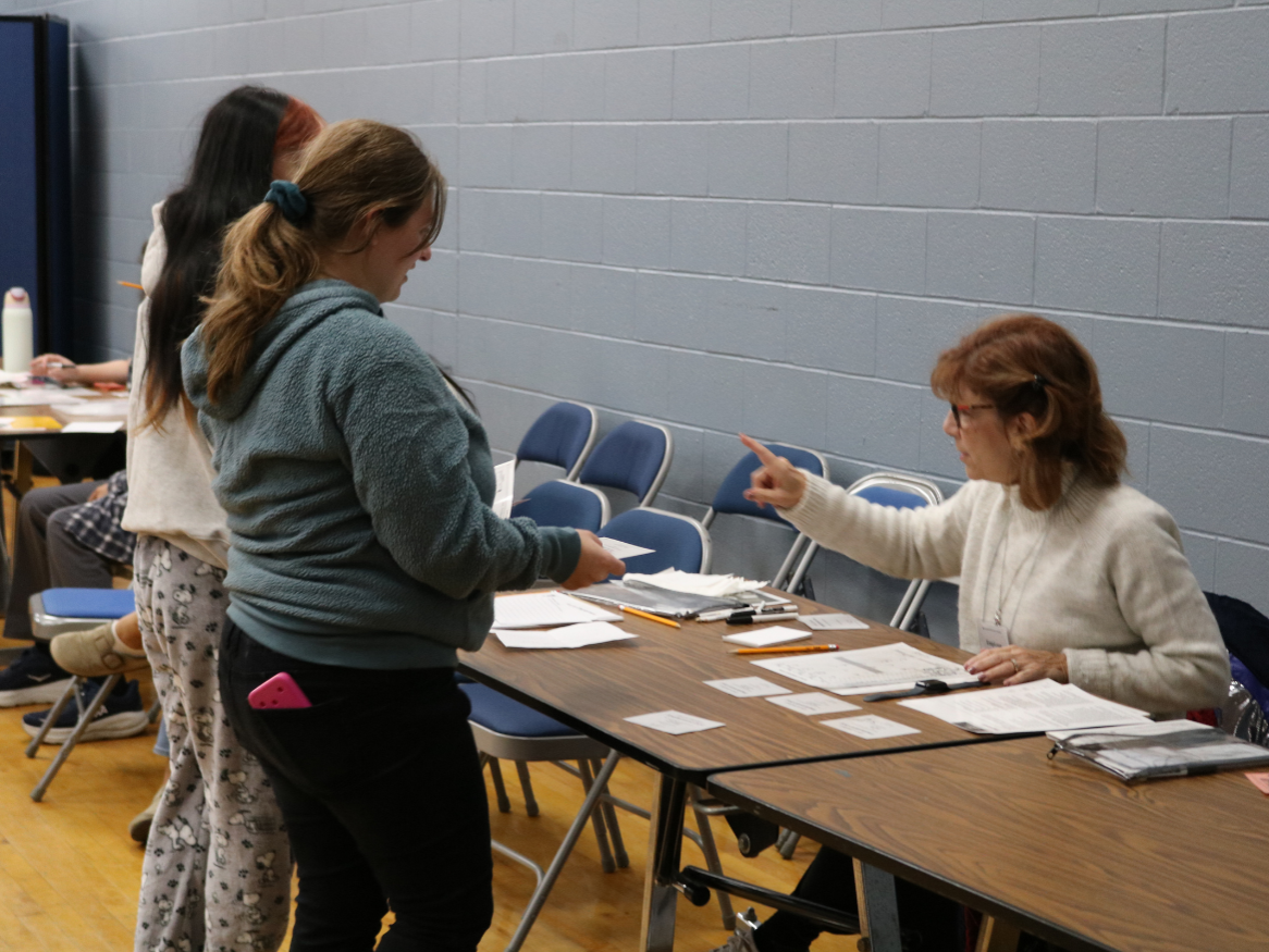 Students talk to a volunteer at a table