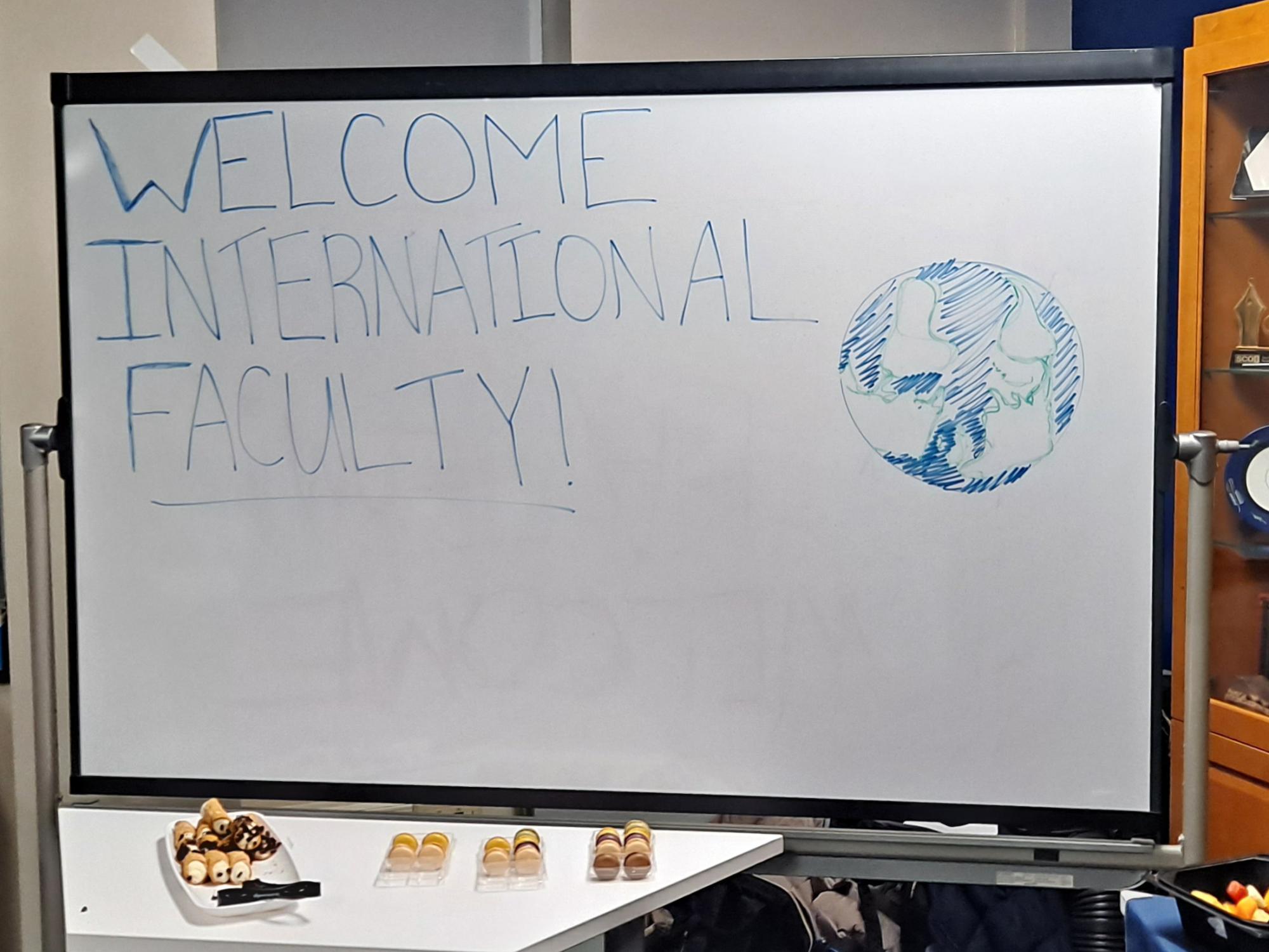 A dry-erase board with "Welcome International Faculty!" written on it. 