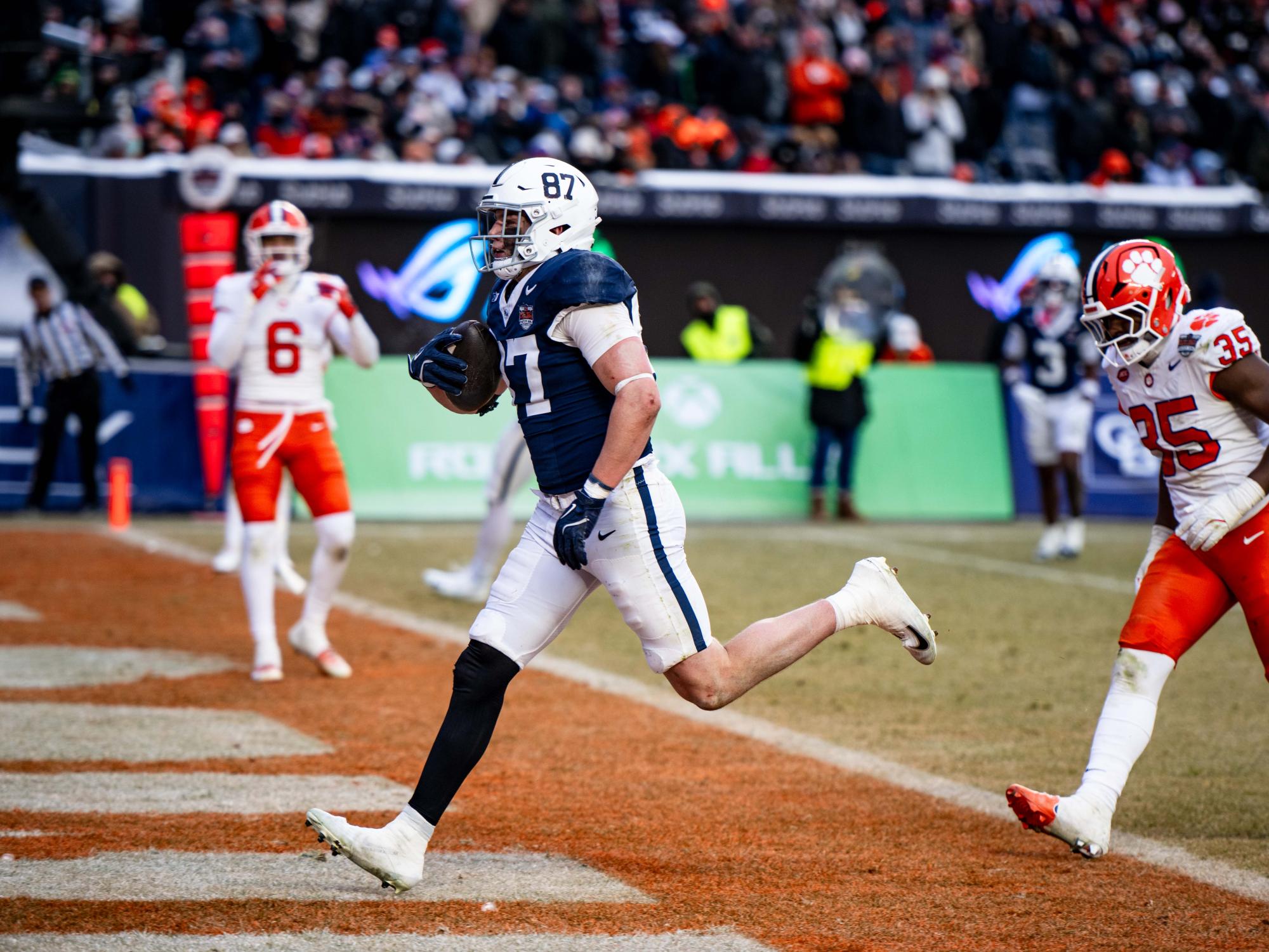 A football player runs into endzone while holding a football 
