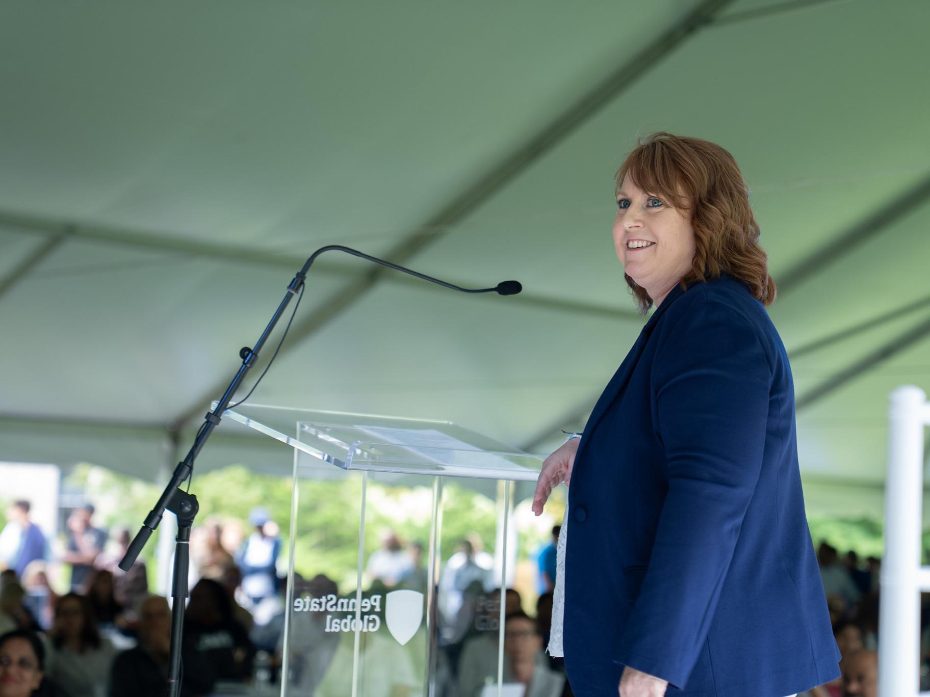 A woman smiling on a stage in front of a crowd