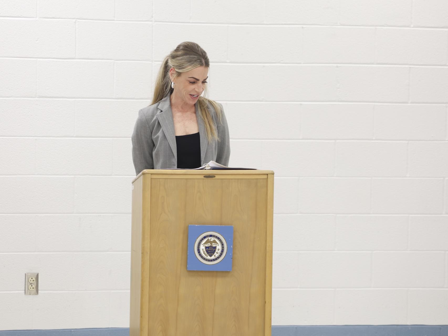 Kelly Shaw speaking behind a podium in the George W. Hill chapel.