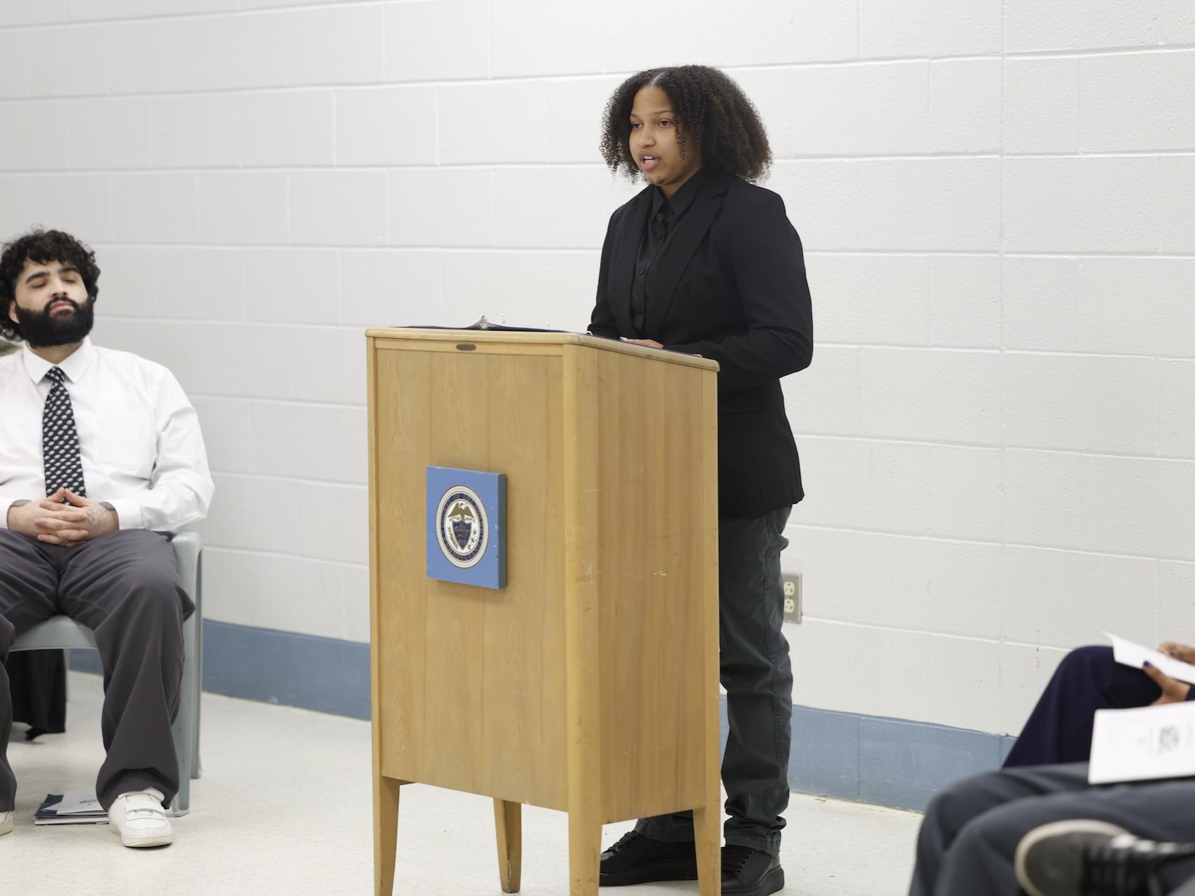 Erika speaking behind a podium in the George W. Hill chapel.