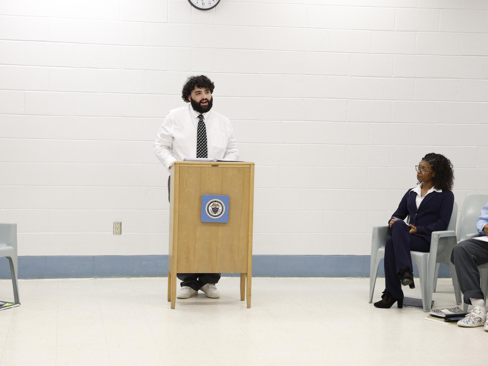 Joseph speaking behind a podium in the George W. Hill chapel.
