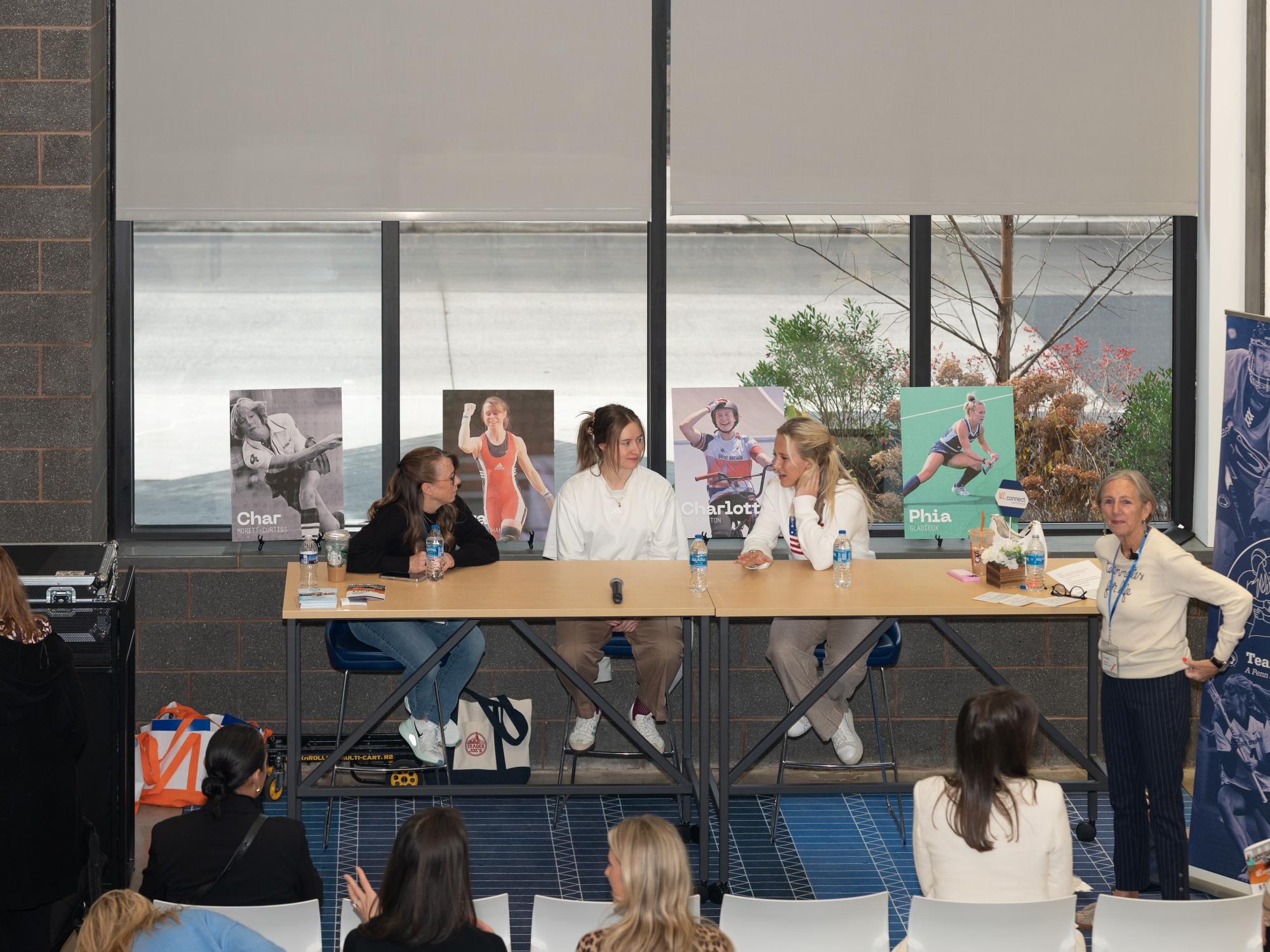 A panel of three individuals sit in front of an audience