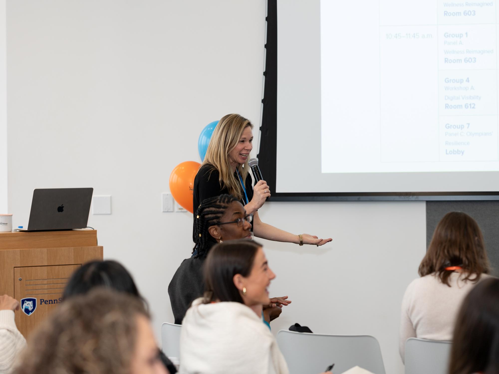 A speaker talks into microphone in front of an audience