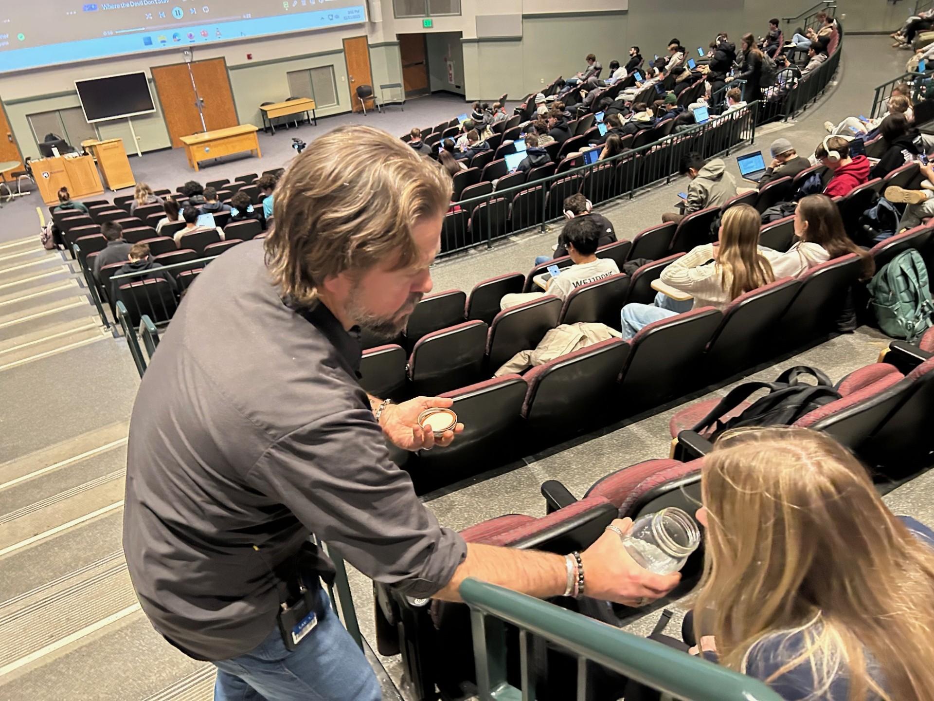 Kirk French holds an open jar of moonshine for a student to smell 