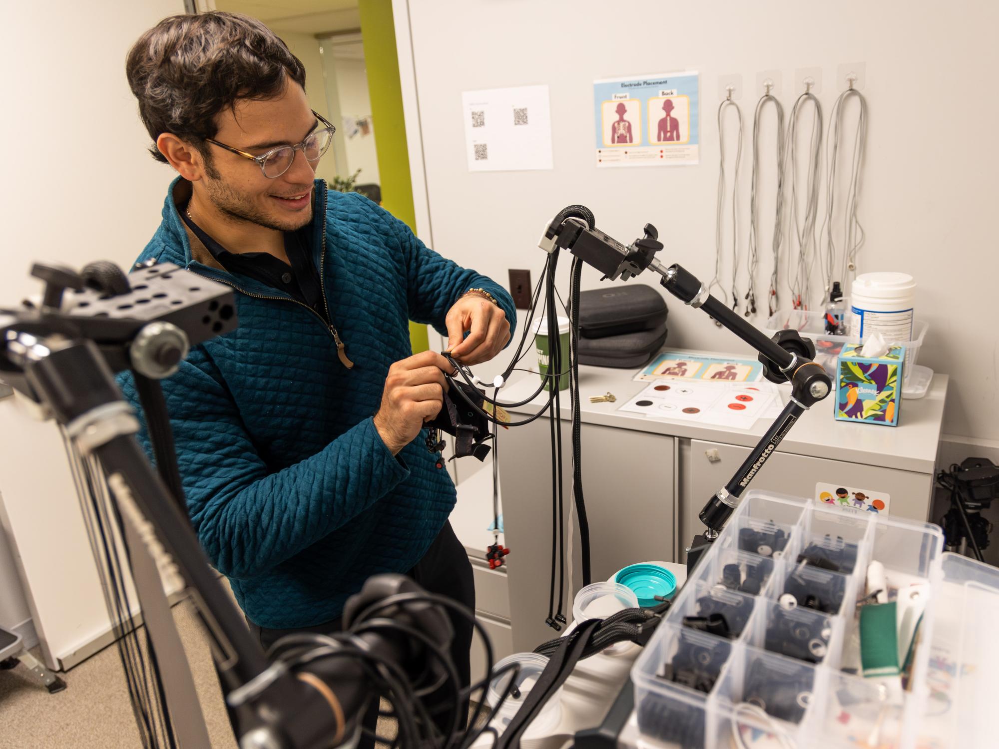 Penn State student Miguel Morazan prepares an fNIRS cap, aligning and securing the optodes in the College of the Liberal Arts' CAT Lab.