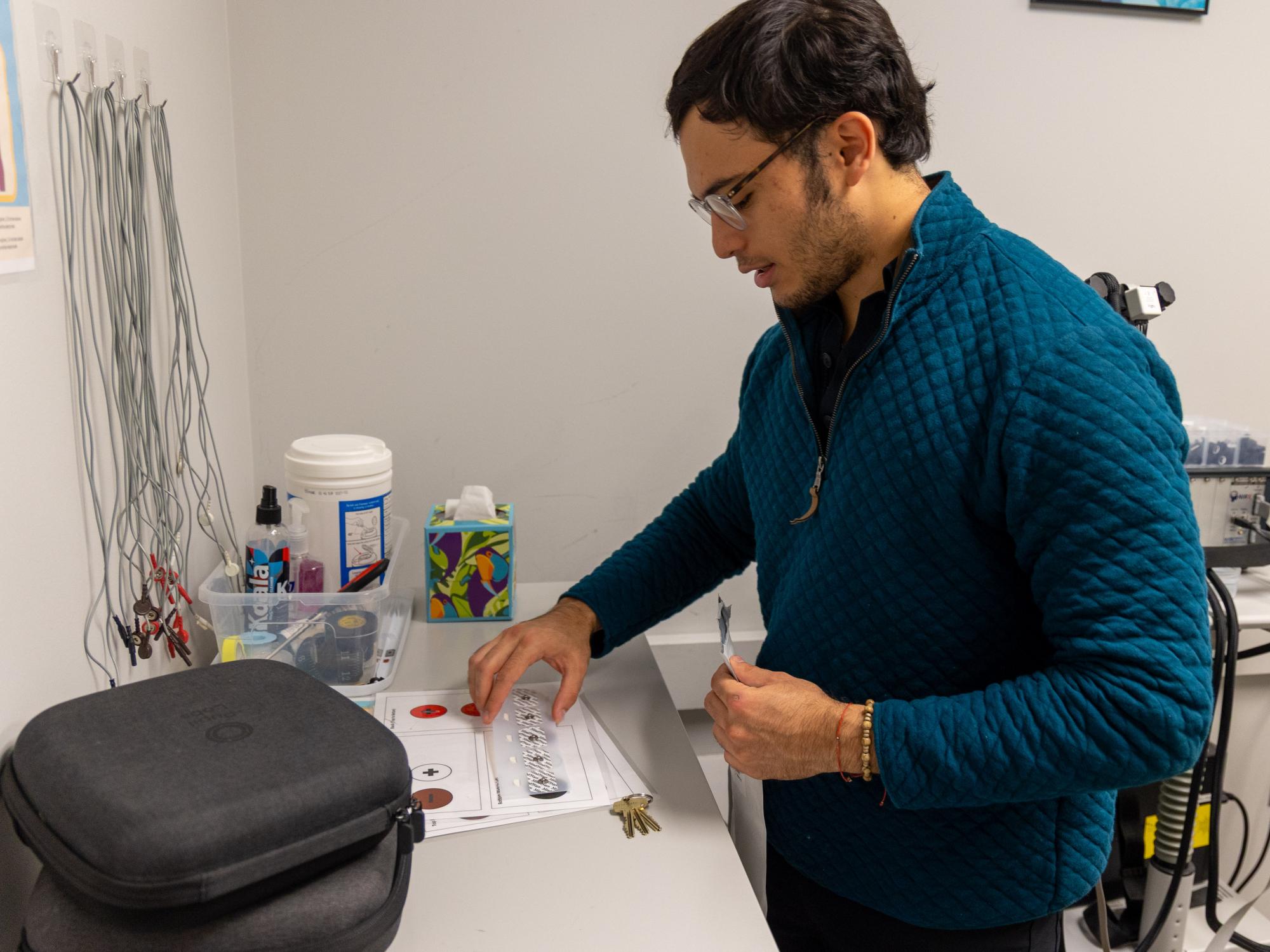 Penn State student Miguel Morazan prepares ECG electrodes and materials for physiological recording in the College of the Liberal Arts' CAT Lab.