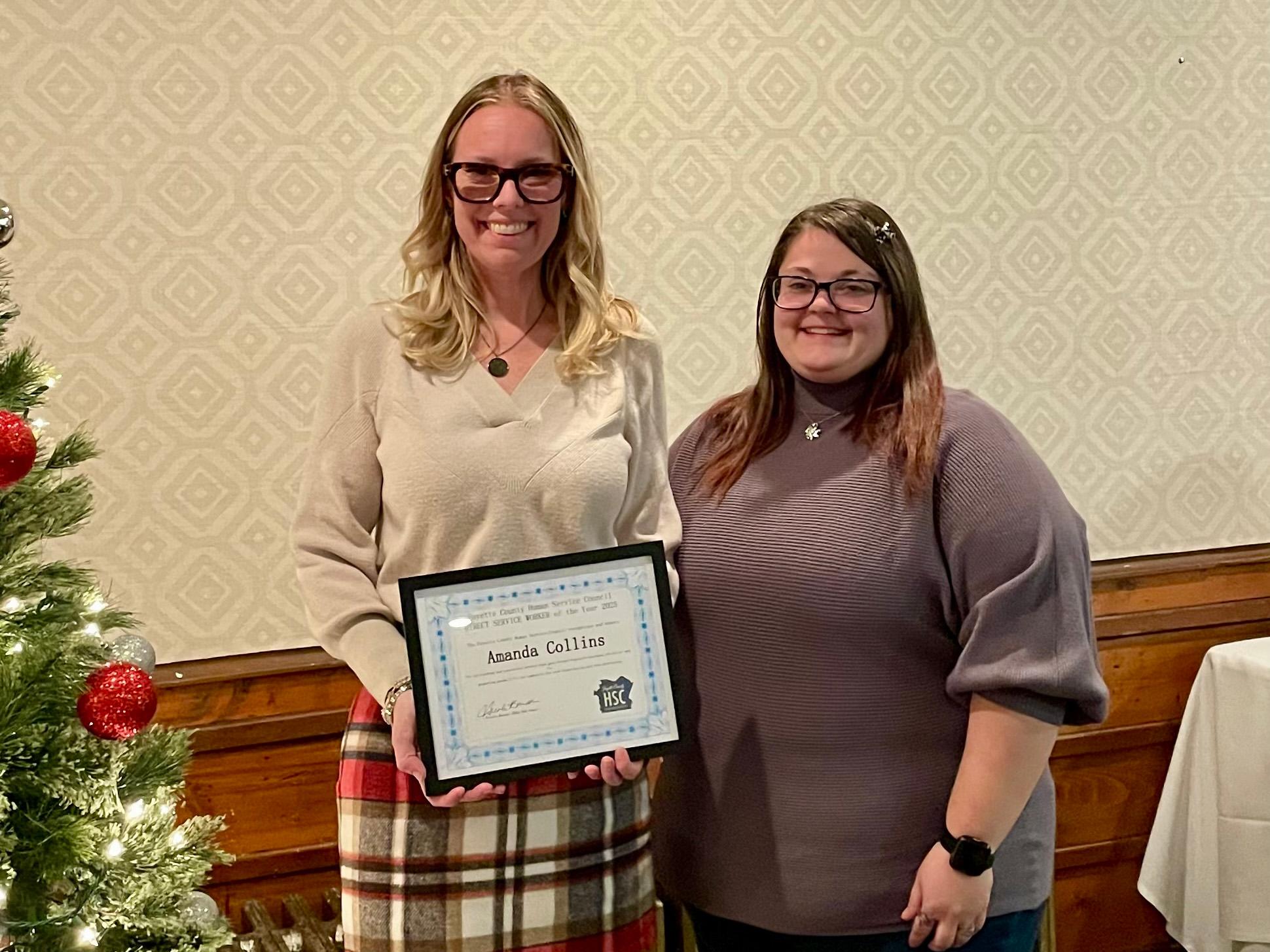 Amanda Collins, left, holds her Direct Service Worker of the Year certificate while standing beside Melissa Andrews at an indoor award presentation.
