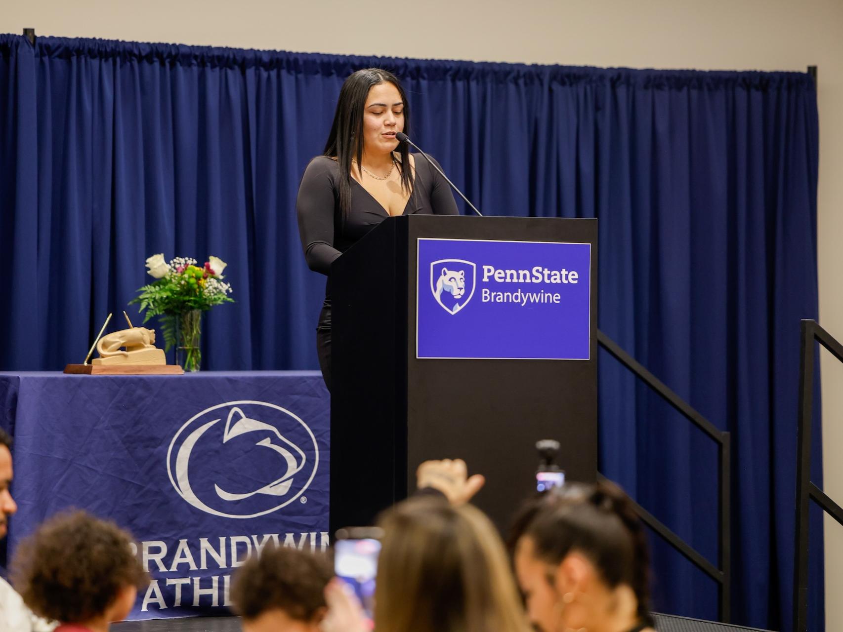 Nikki Velez speaking at a podium that says Penn State Brandywine after receiving her award. 