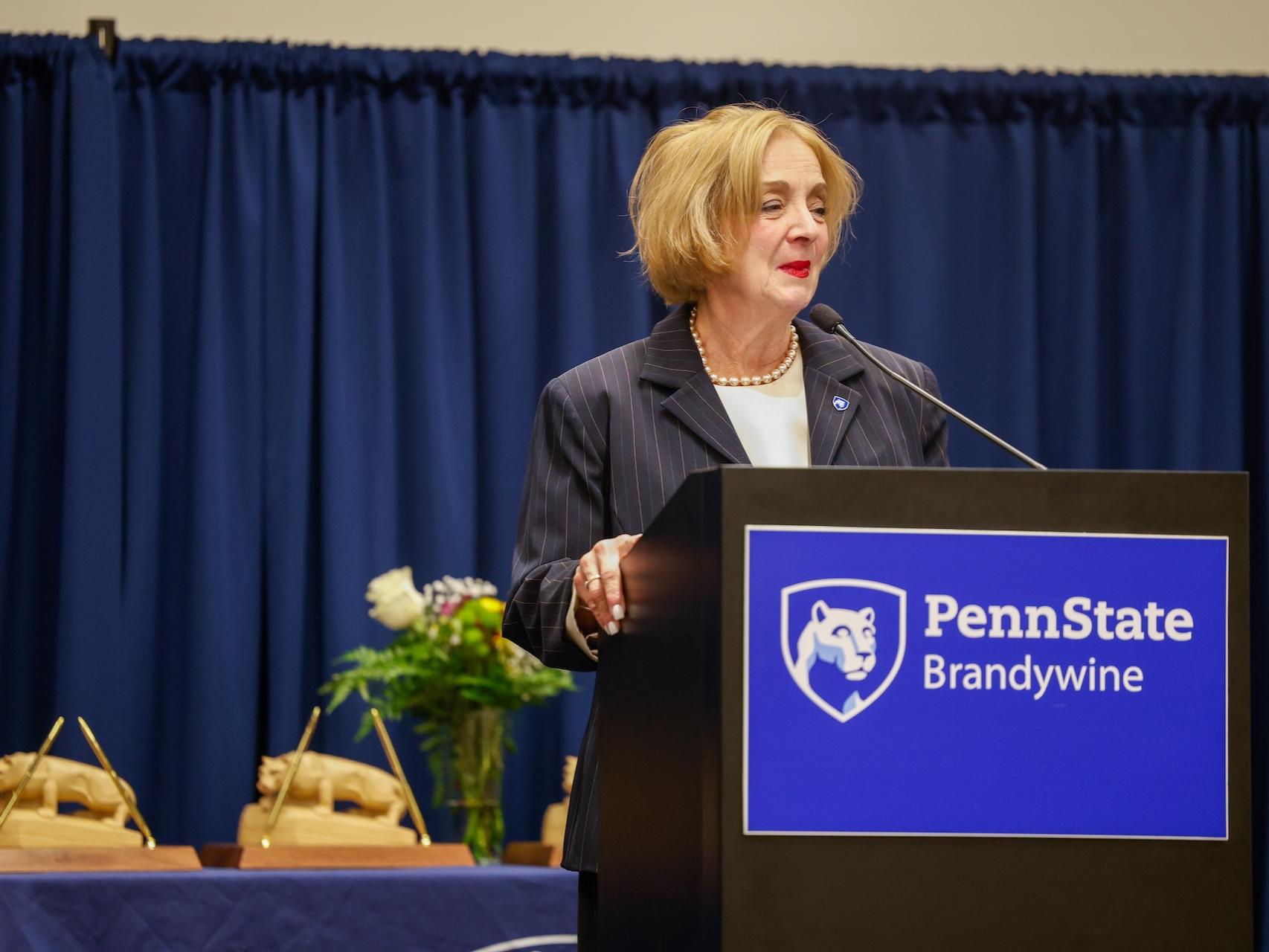 Marilyn Wells talking at a podium that says Penn State Brandywine