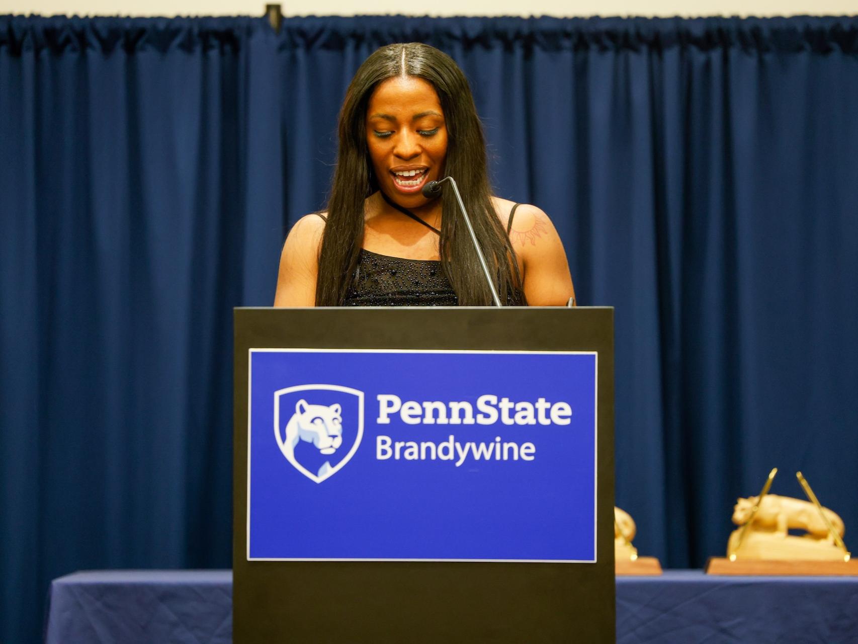 Brianna Banks speaking at a podium that says Penn State Brandywine after receiving her award. 