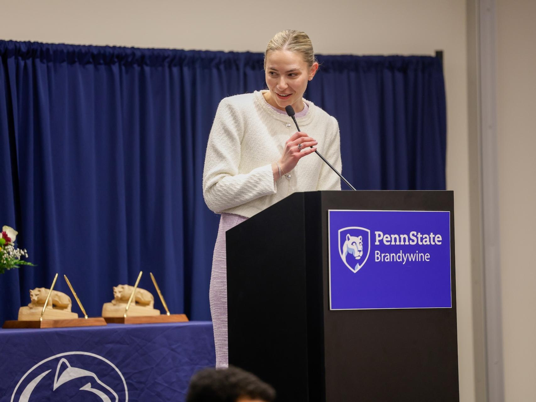 Katie DeStefano speaking at a podium that says Penn State Brandywine after receiving her award. 