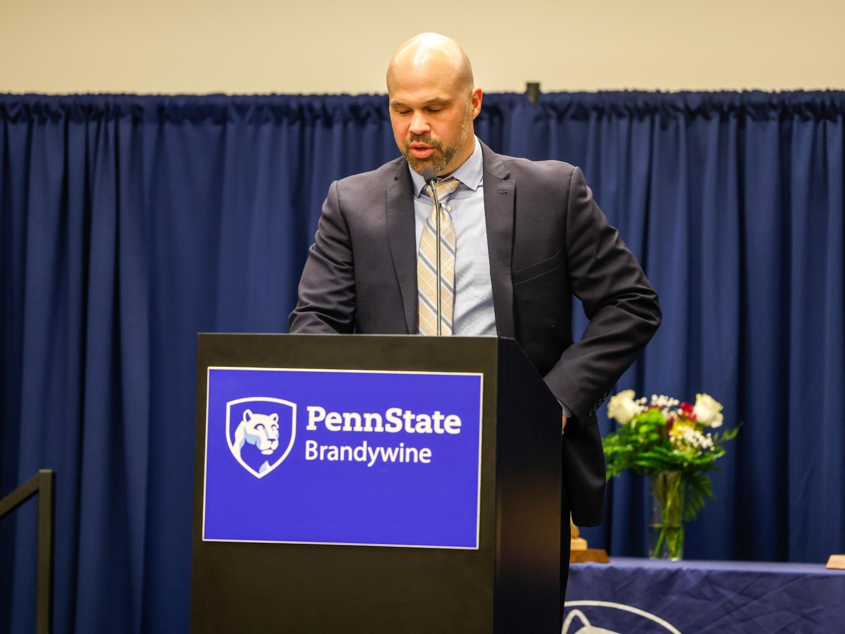 Frank Flaim speaking at a podium that says Penn State Brandywine after receiving his award. 