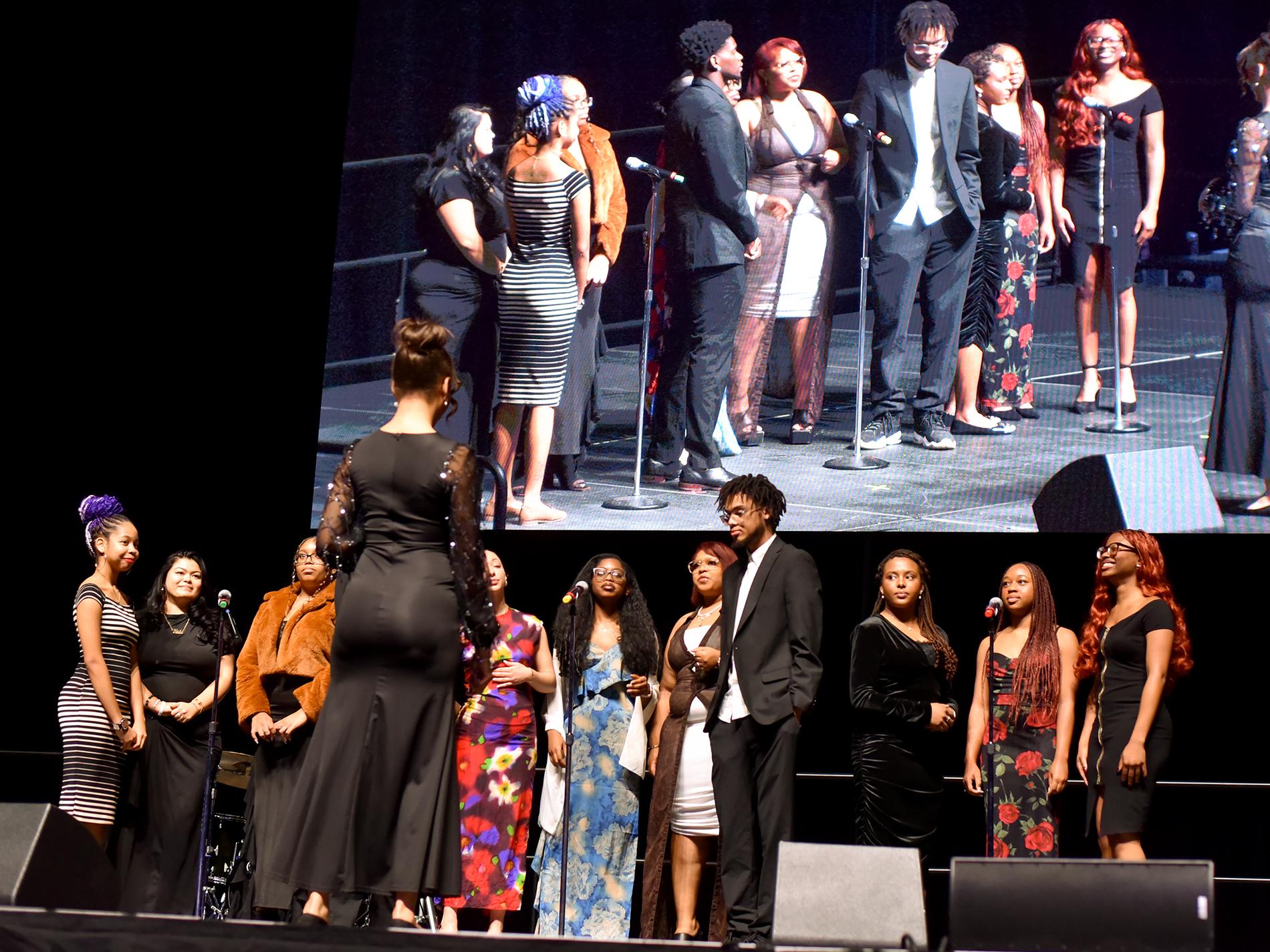 United Christian Campus Ministry Choir performs on stage with a screen behind them