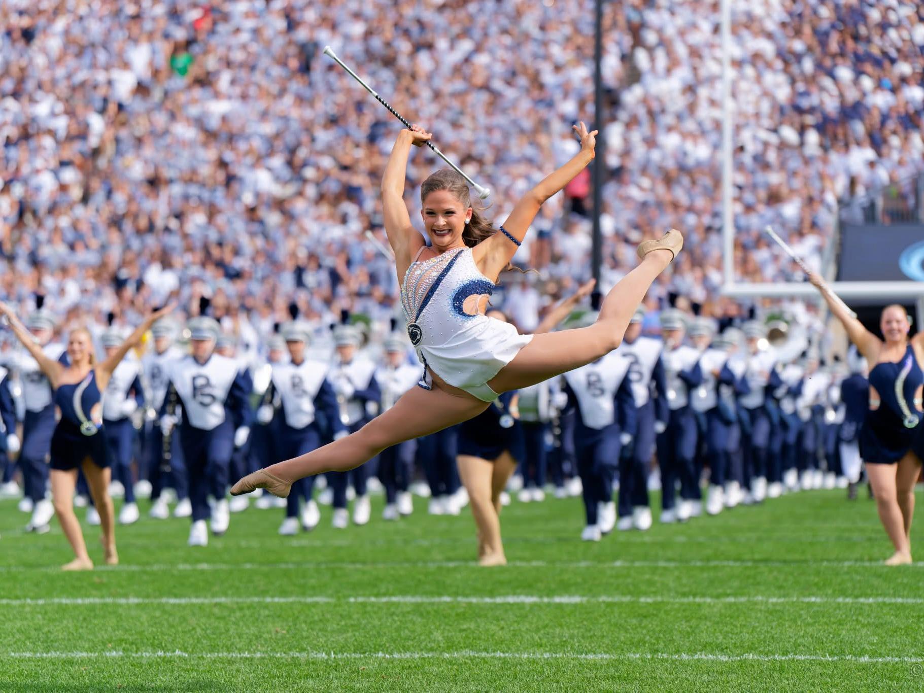 Featured twirler Mackenzie Bronk leaps into the air during a performance in Beaver Stadium.