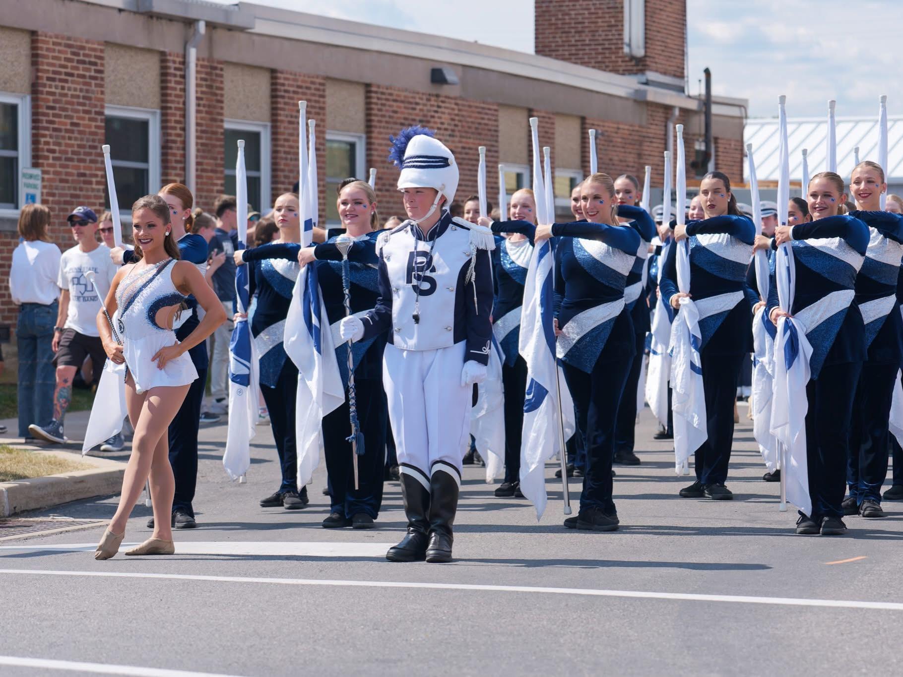 Penn State Blue Band's Featured twirler Mackenzie Bronk and drum major Ellie Sheehan lead the way in a parade