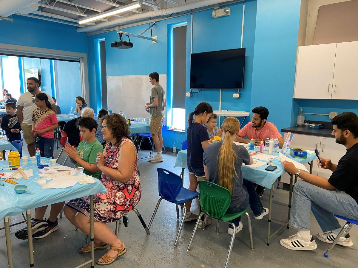 Group of people working in a room at various tables on science projects