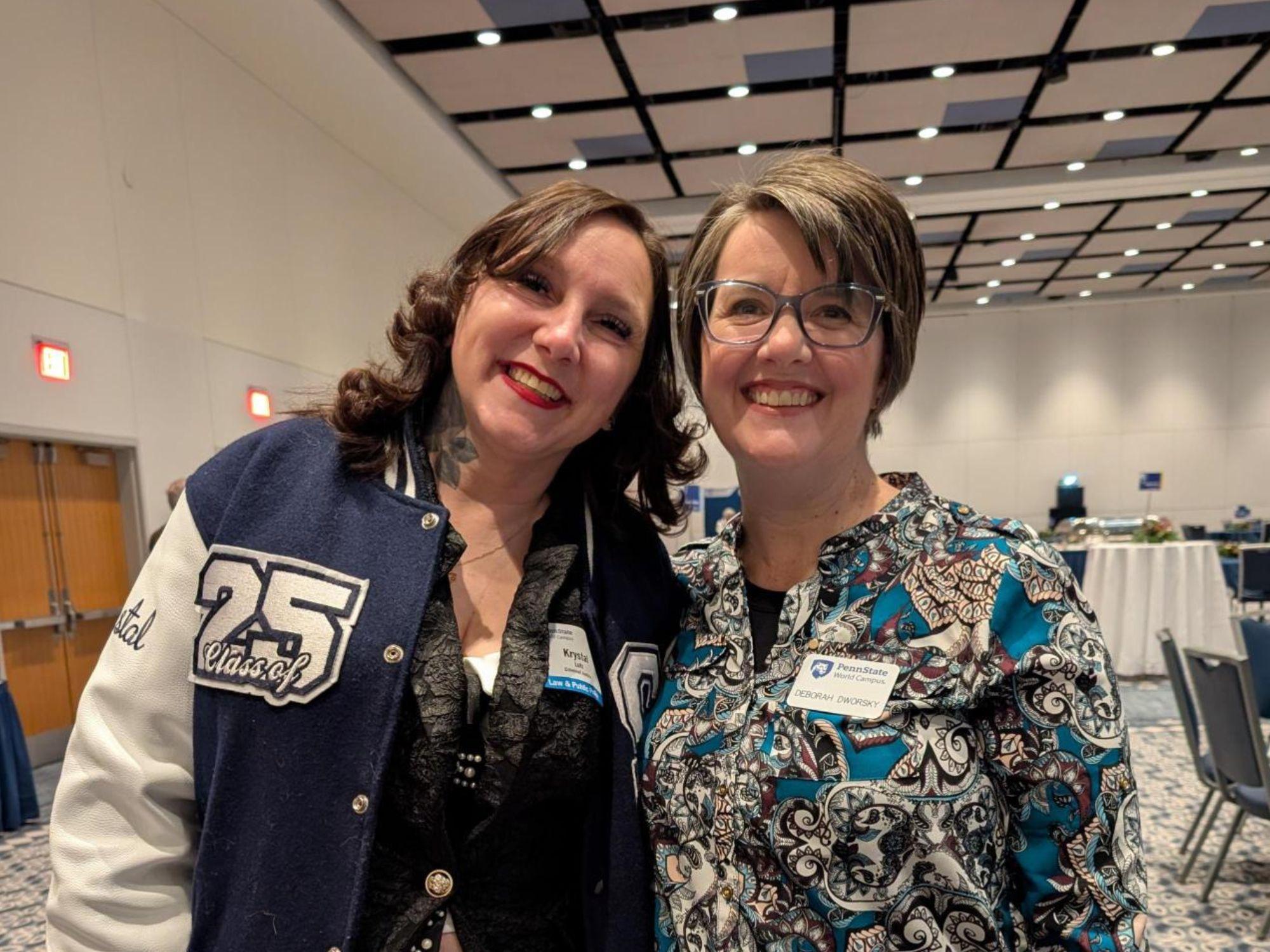 a woman in a jacket stands next to a woman with a nametag on her lapel